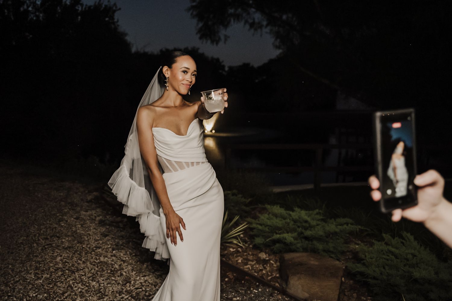Two people share an intimate moment on a wedding day with a dramatic evening sky backdrop.