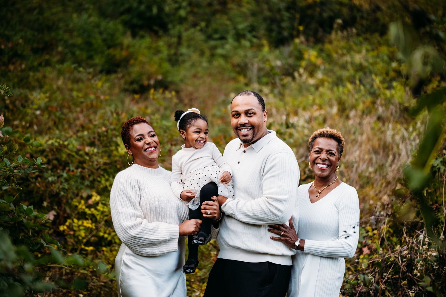 A family group shares laughter while posing together outdoors.