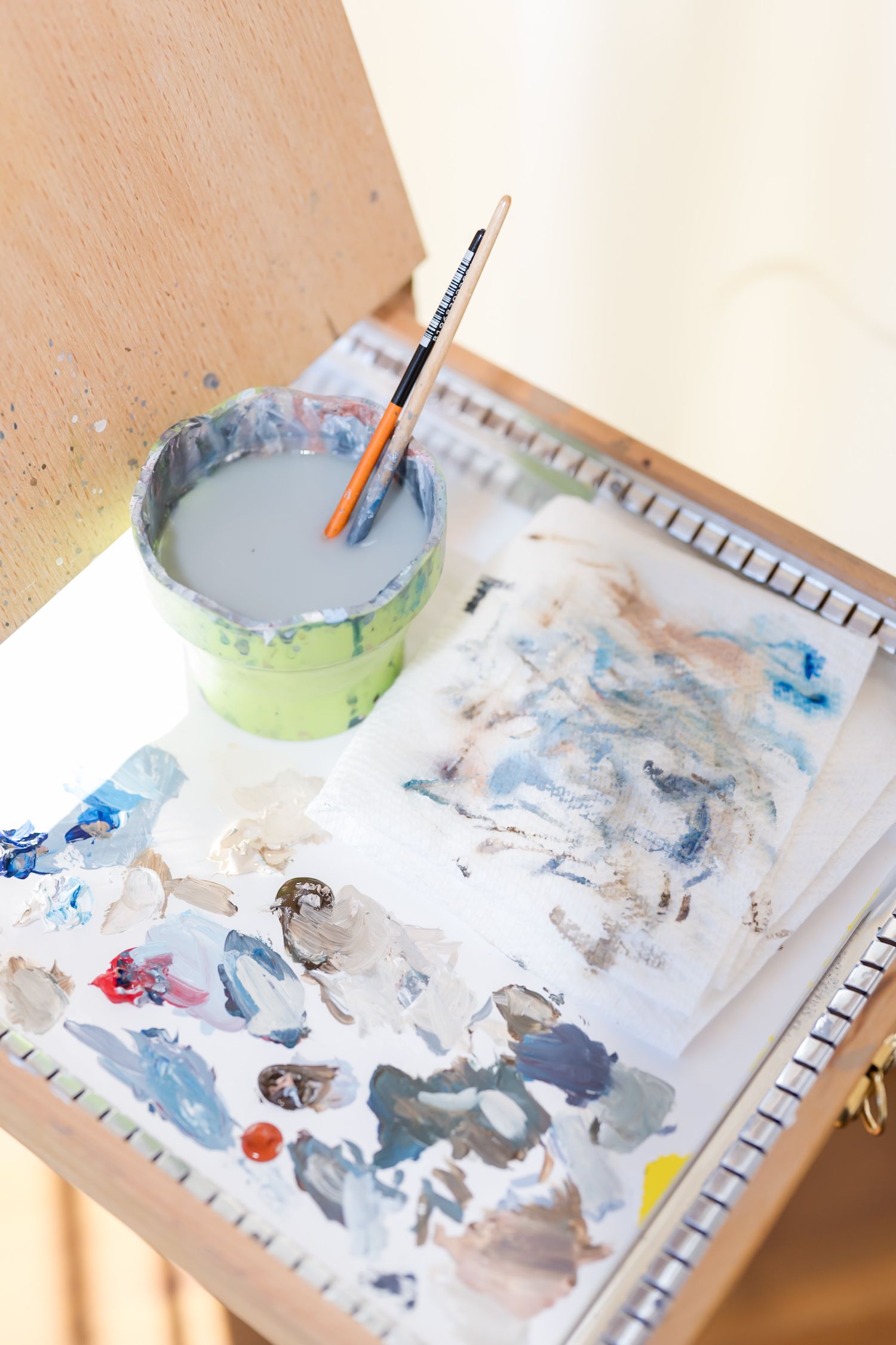 Watercolor paint palette showing mixed blue and gray tones with brushes.