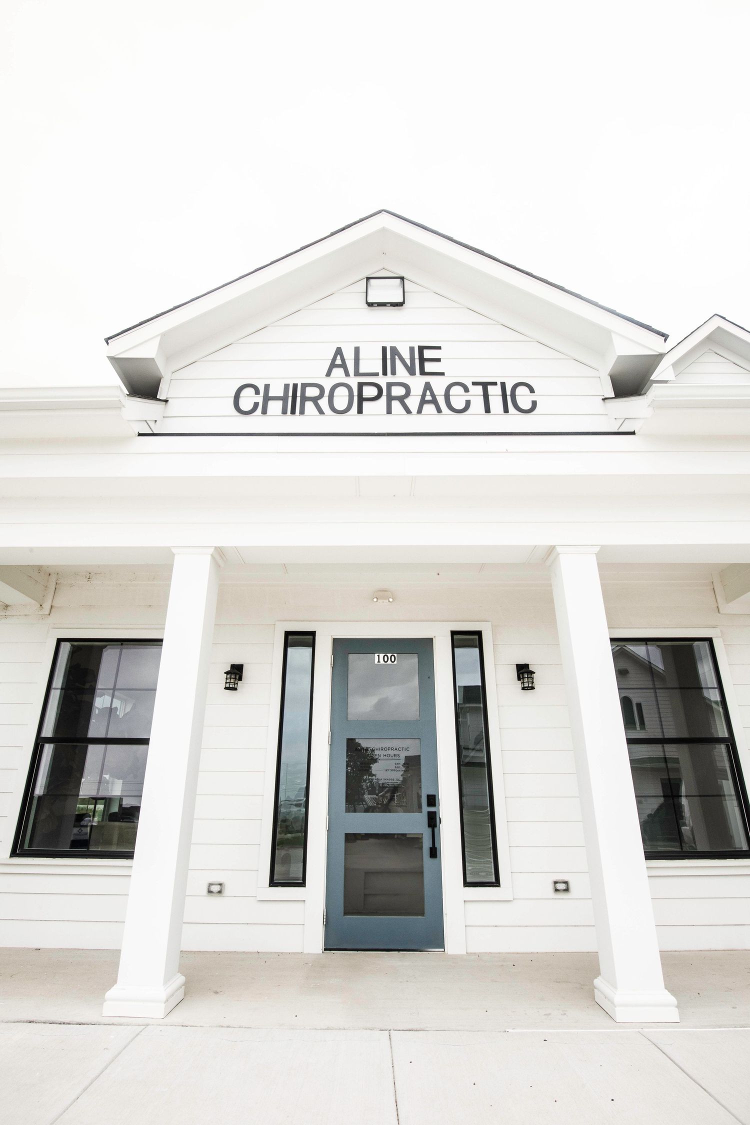 Exterior view of Aline Chiropractic office building with white facade and colonial style architecture.