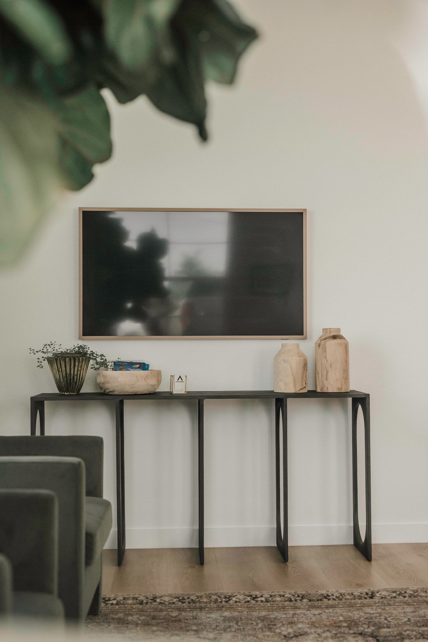 Modern black console tables arranged against white wall with indoor plants.
