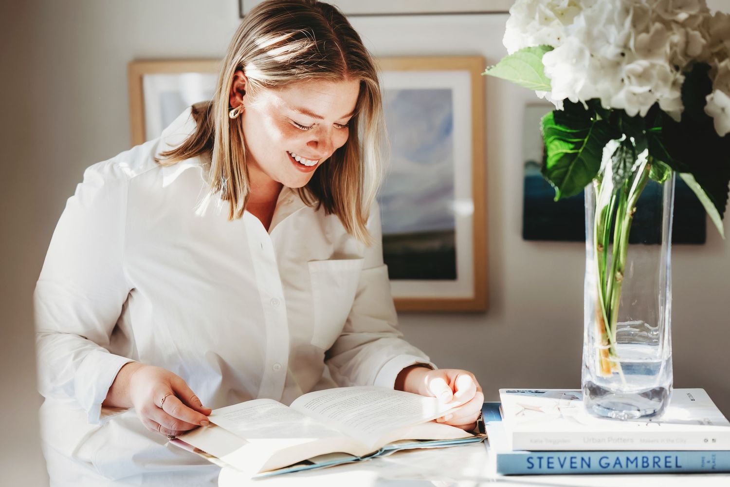 Interior office scene with white flowers and desk accessories in natural lighting.