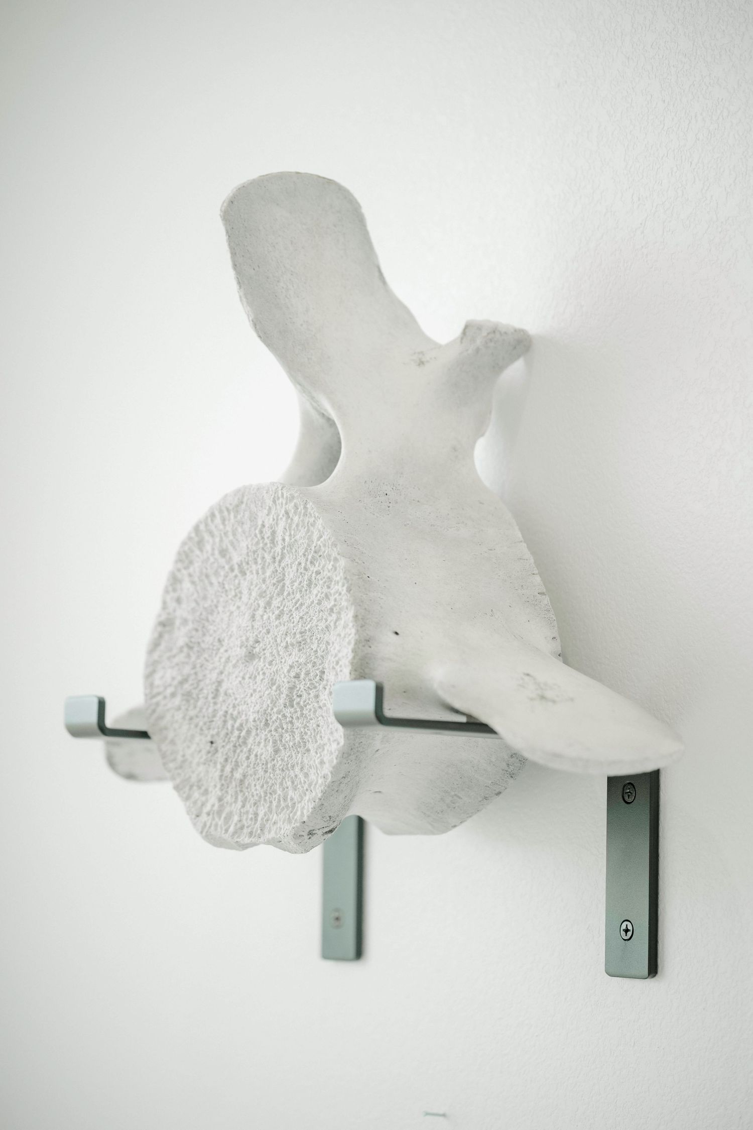 White cloud-shaped wall sculpture mounted on gray metal brackets against a white background.