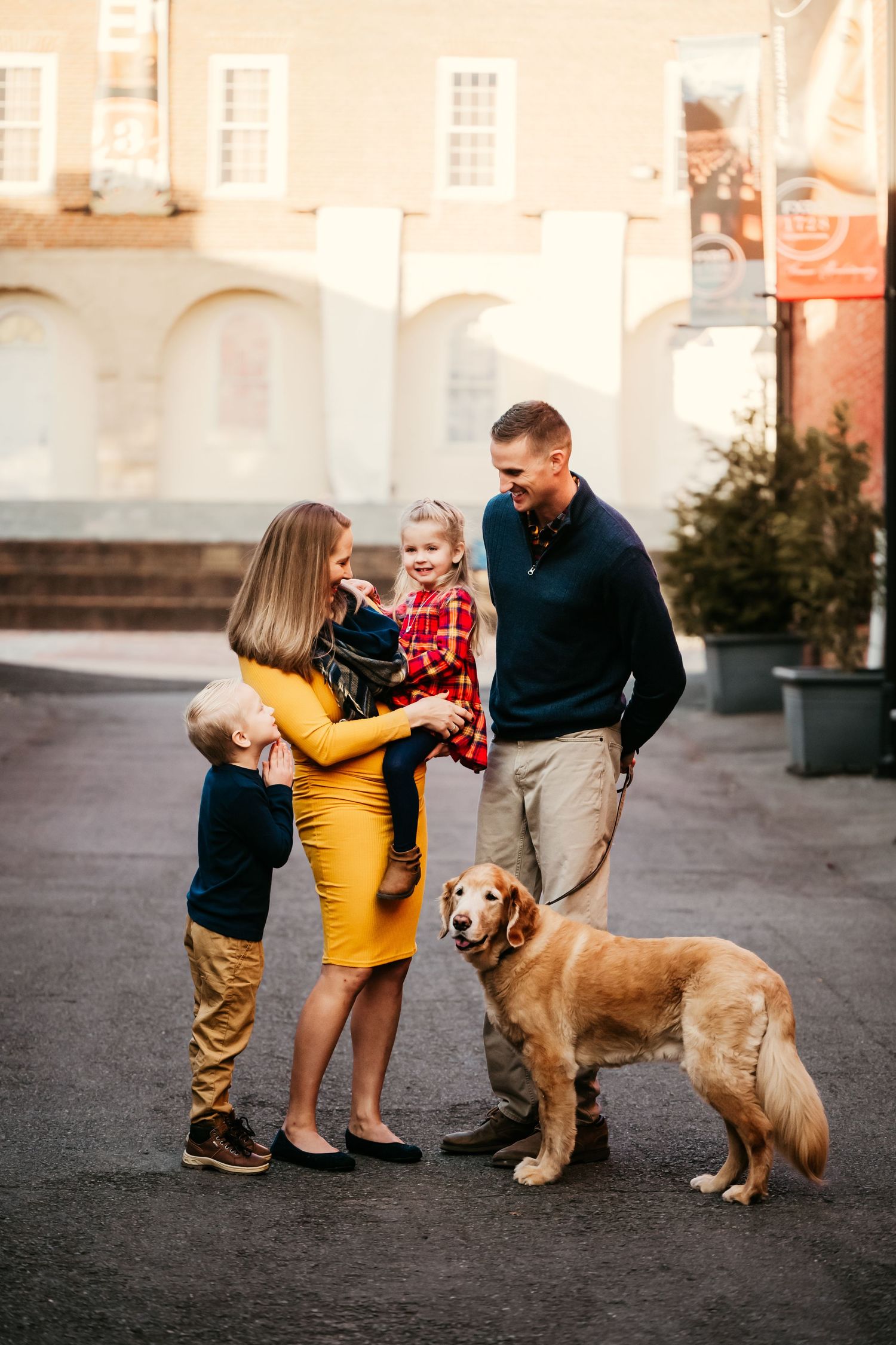 Warm sunset family photos with golden retriever against historic building backdrop.