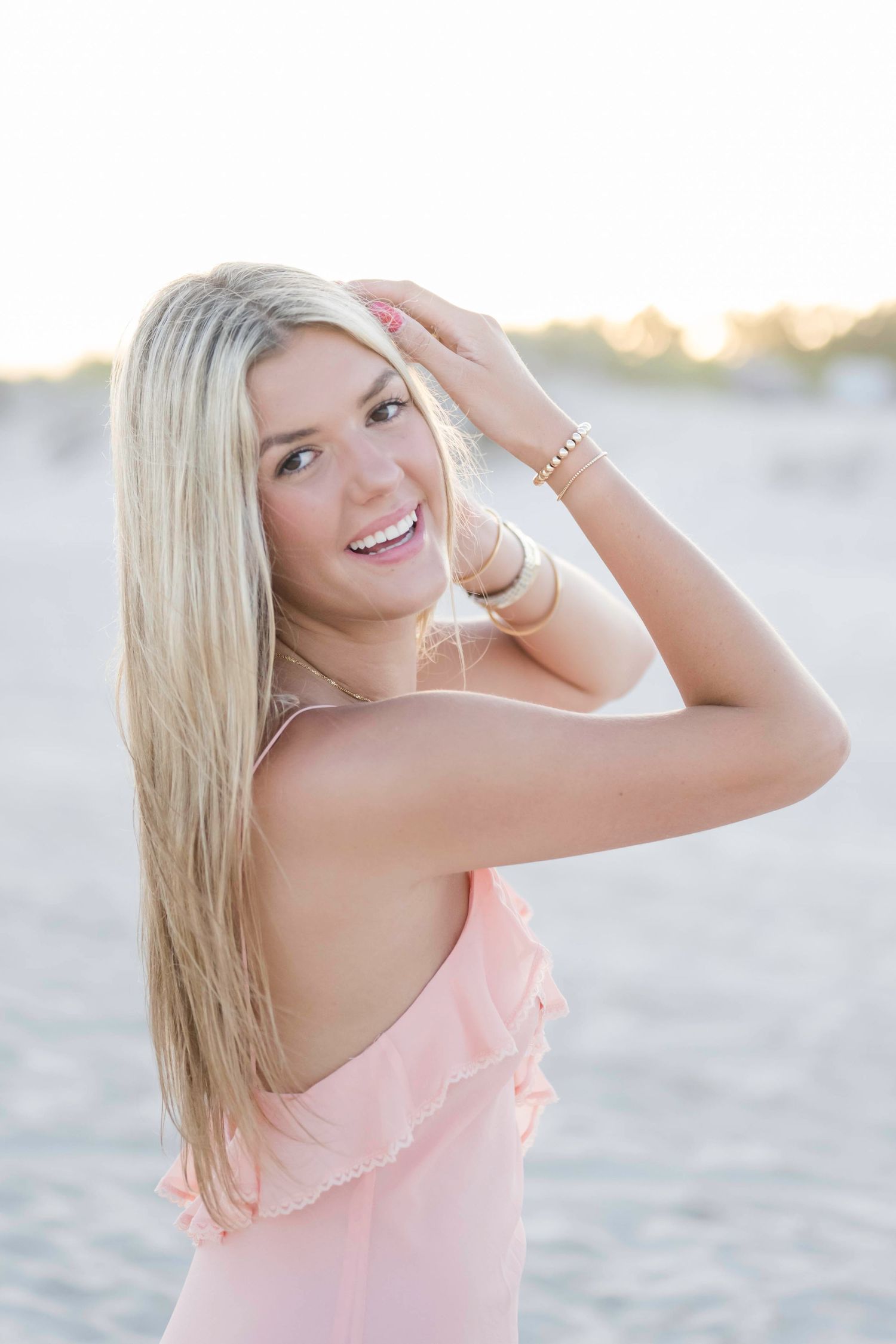 A peach-colored dress flows in the gentle ocean breeze during a beach sunset photoshoot.