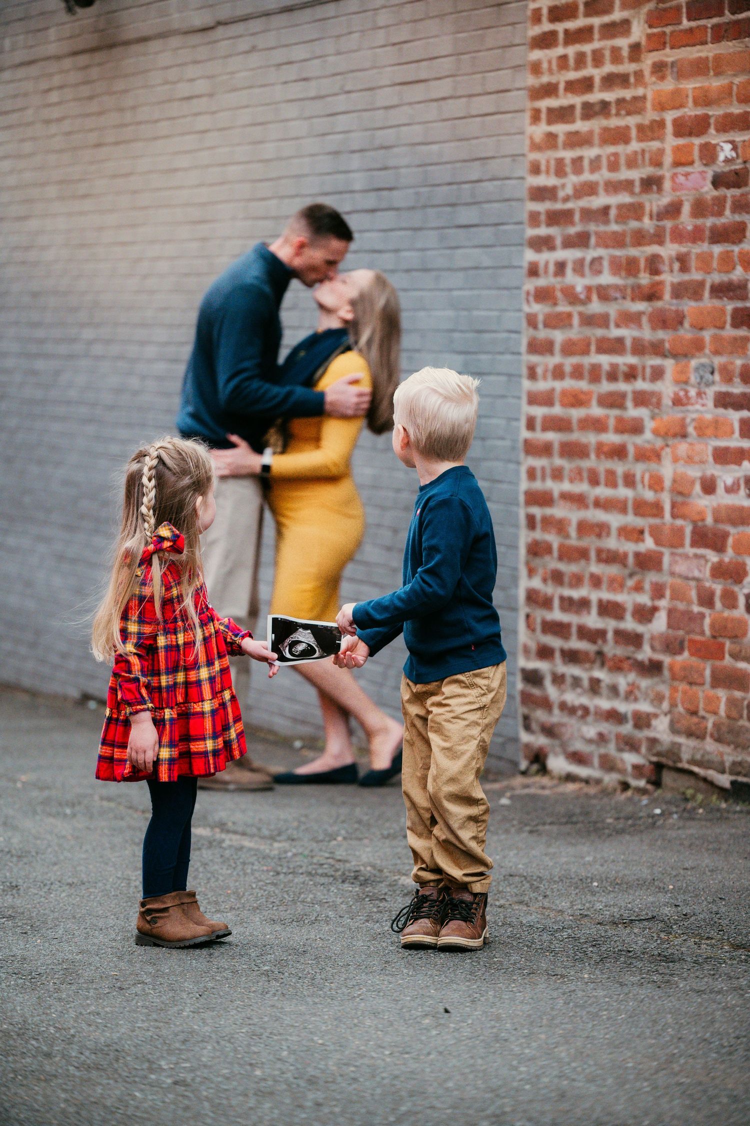 Family interaction series against grey brick wall in coordinated casual outfits.