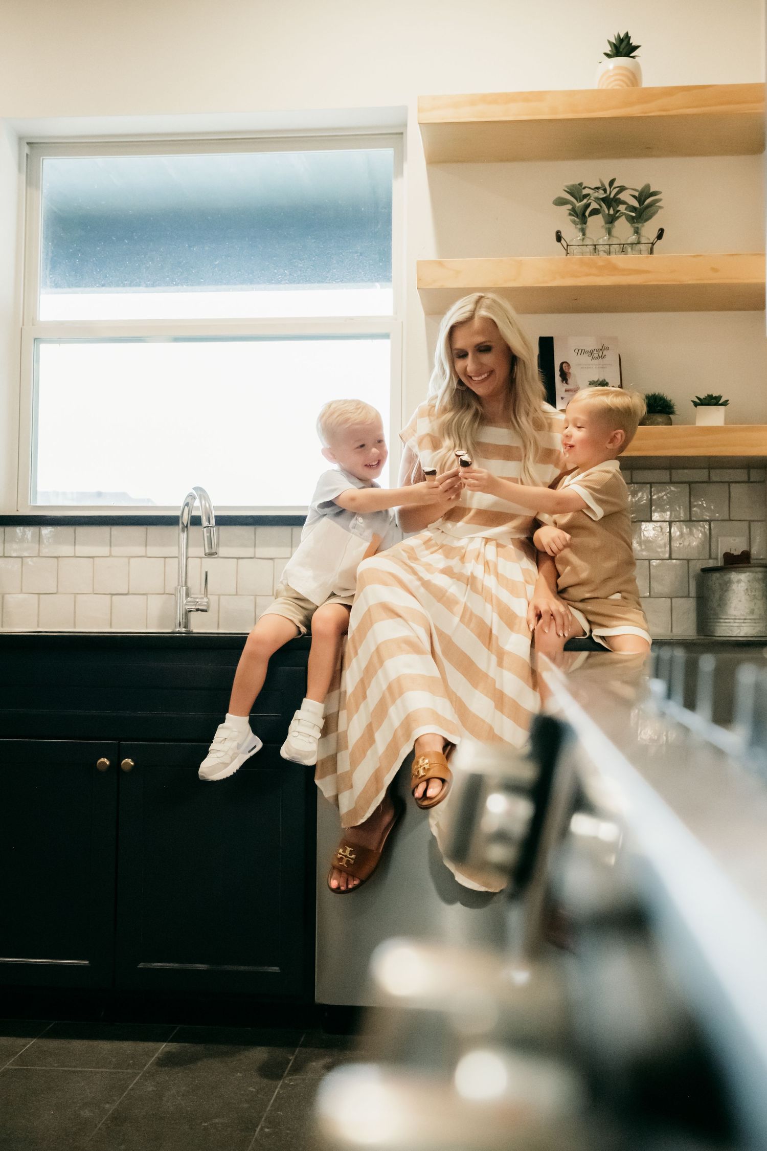 A series of five connected photos showing playful moments in a modern white kitchen with natural lighting.