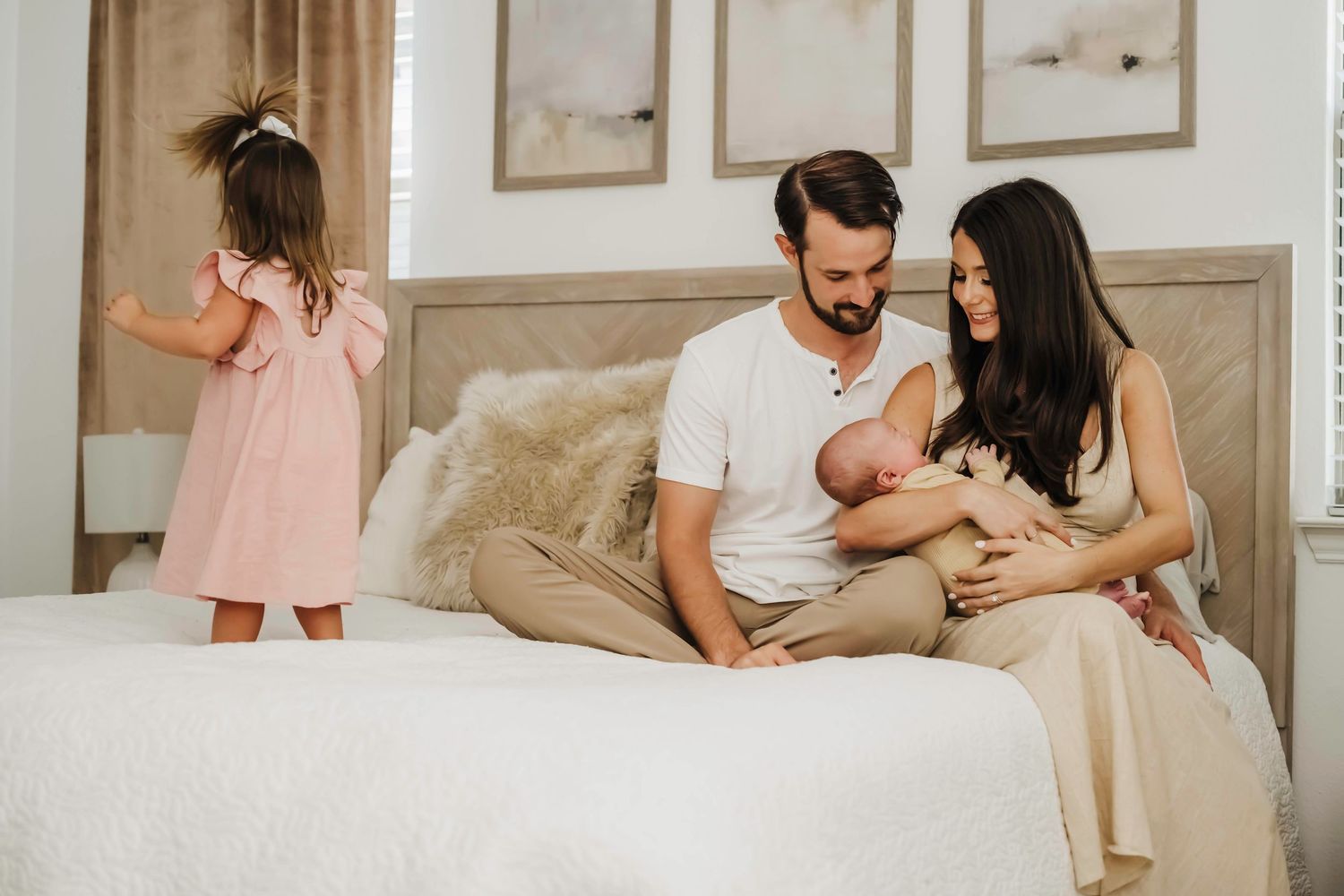 A cozy family moment captured on a neutral-toned bed during an intimate photoshoot.
