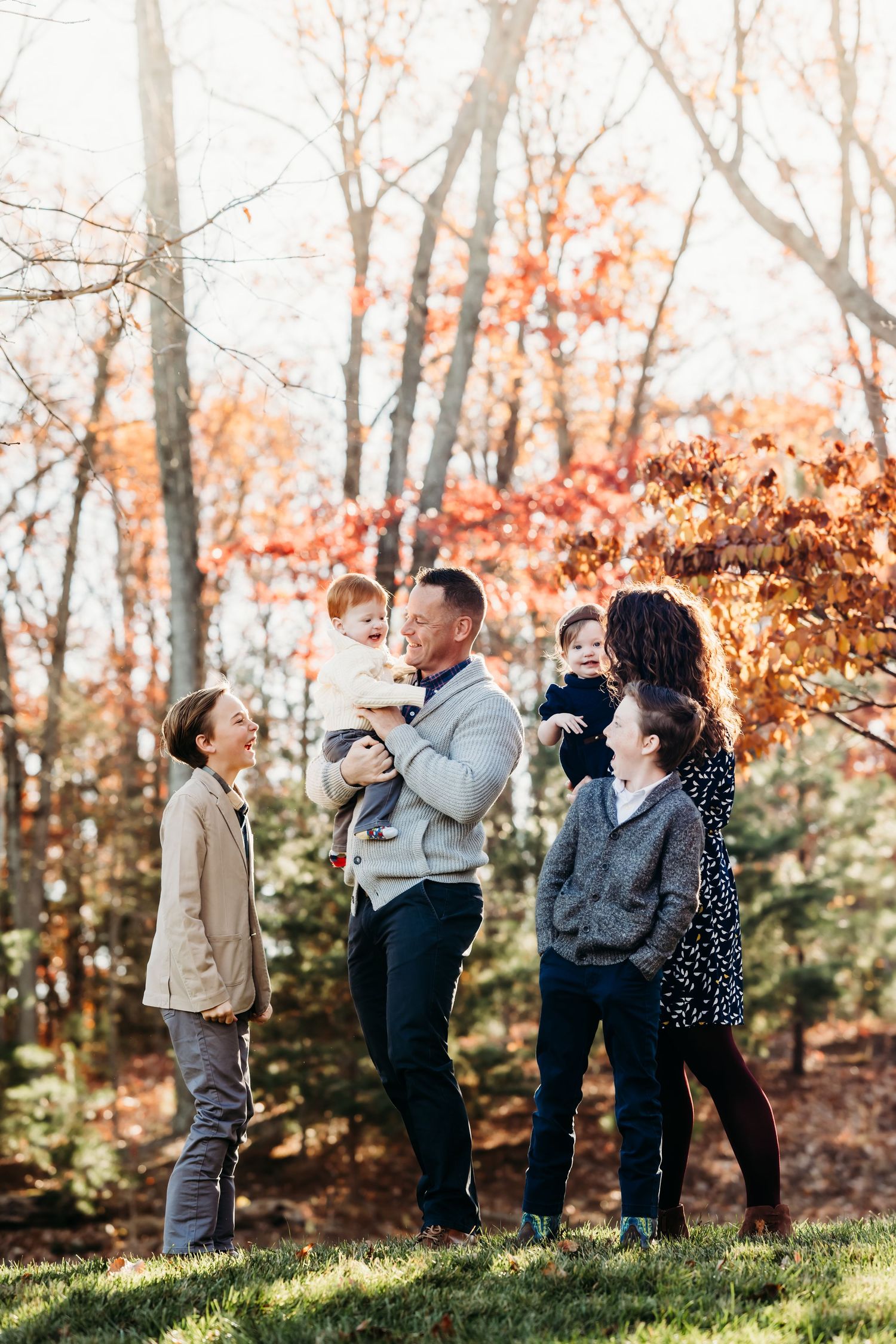 Family group portrait session among autumn trees with golden afternoon light.
