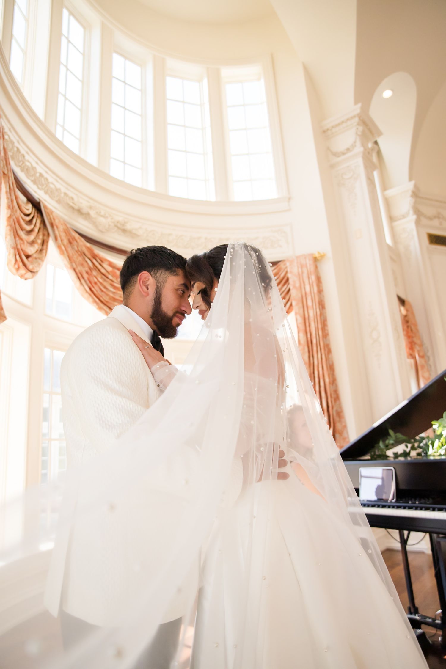 Elegant ballroom interior with flowing white curtains and grand piano in natural light.