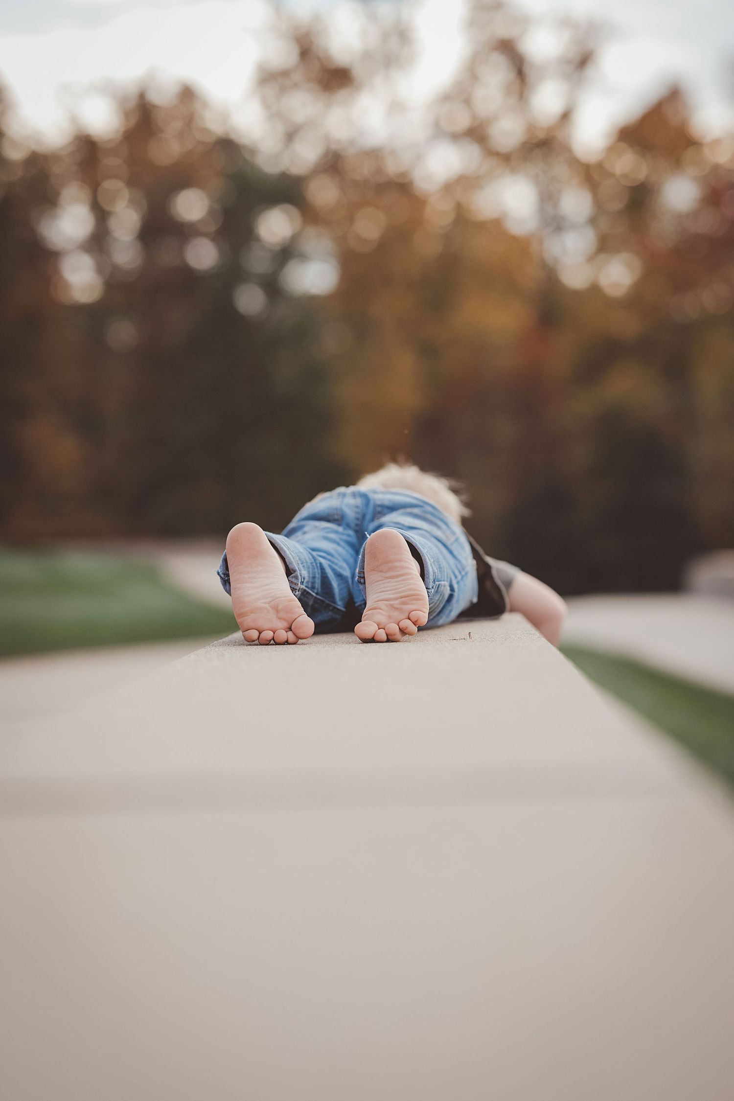 Two feet peeking out from behind a concrete wall during a creative outdoor photoshoot in autumn.