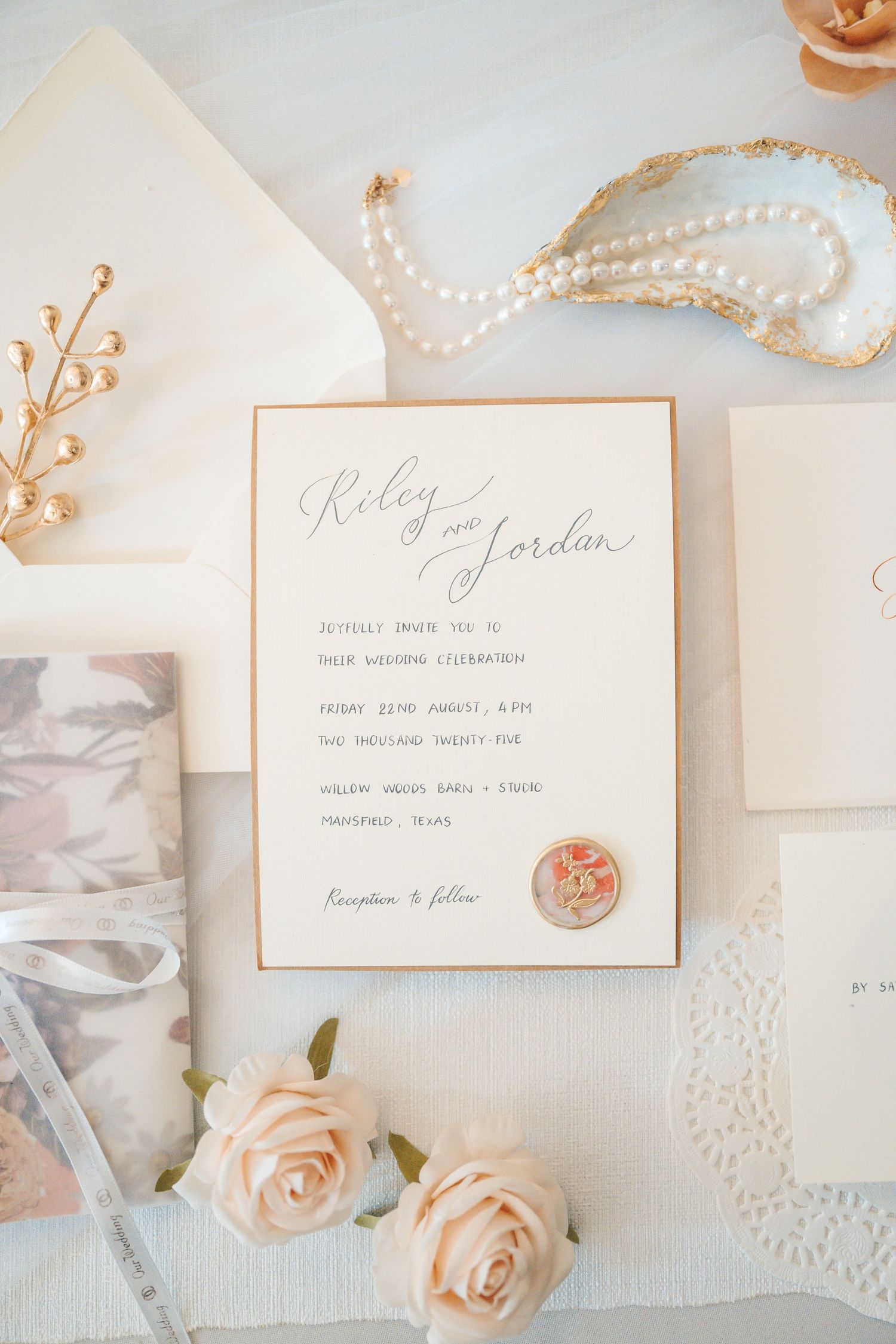 Elegant wedding invitation suite with delicate roses, pearls, and calligraphy on white lace background.