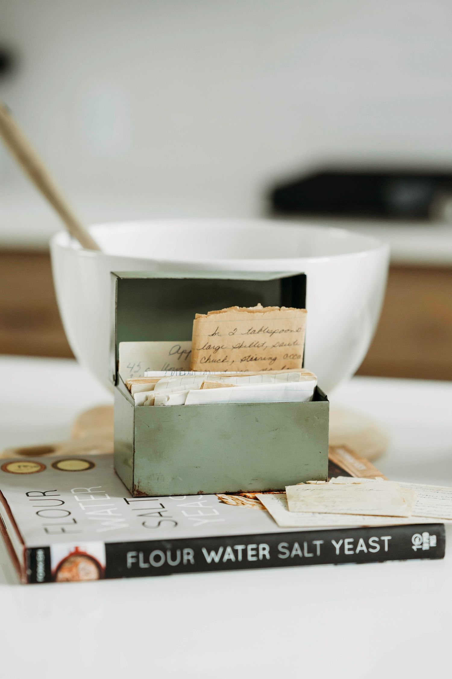 Vintage recipe box and baking ingredients arranged on wooden surface.