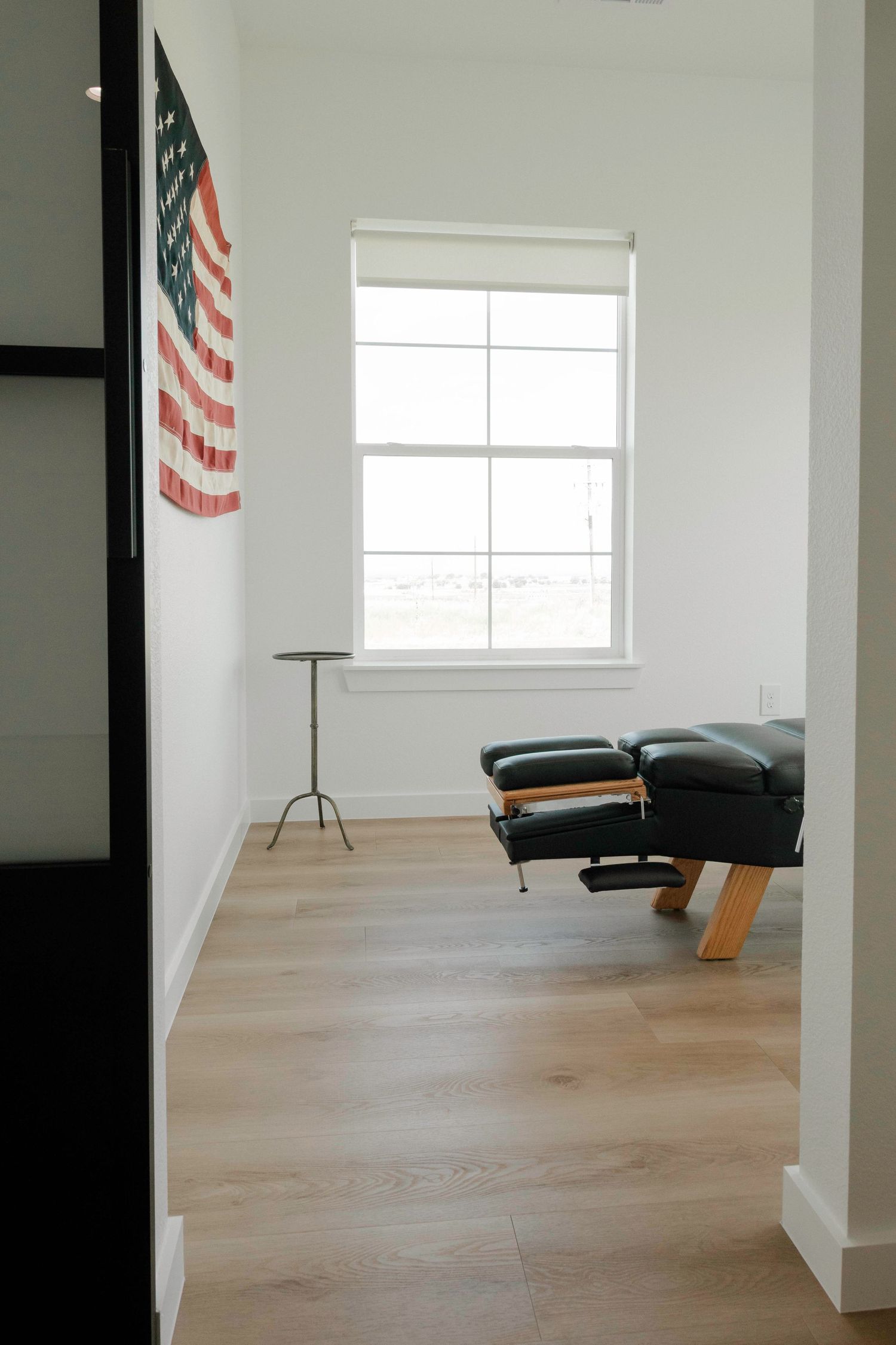 Empty room with light wood flooring and white walls featuring windows.