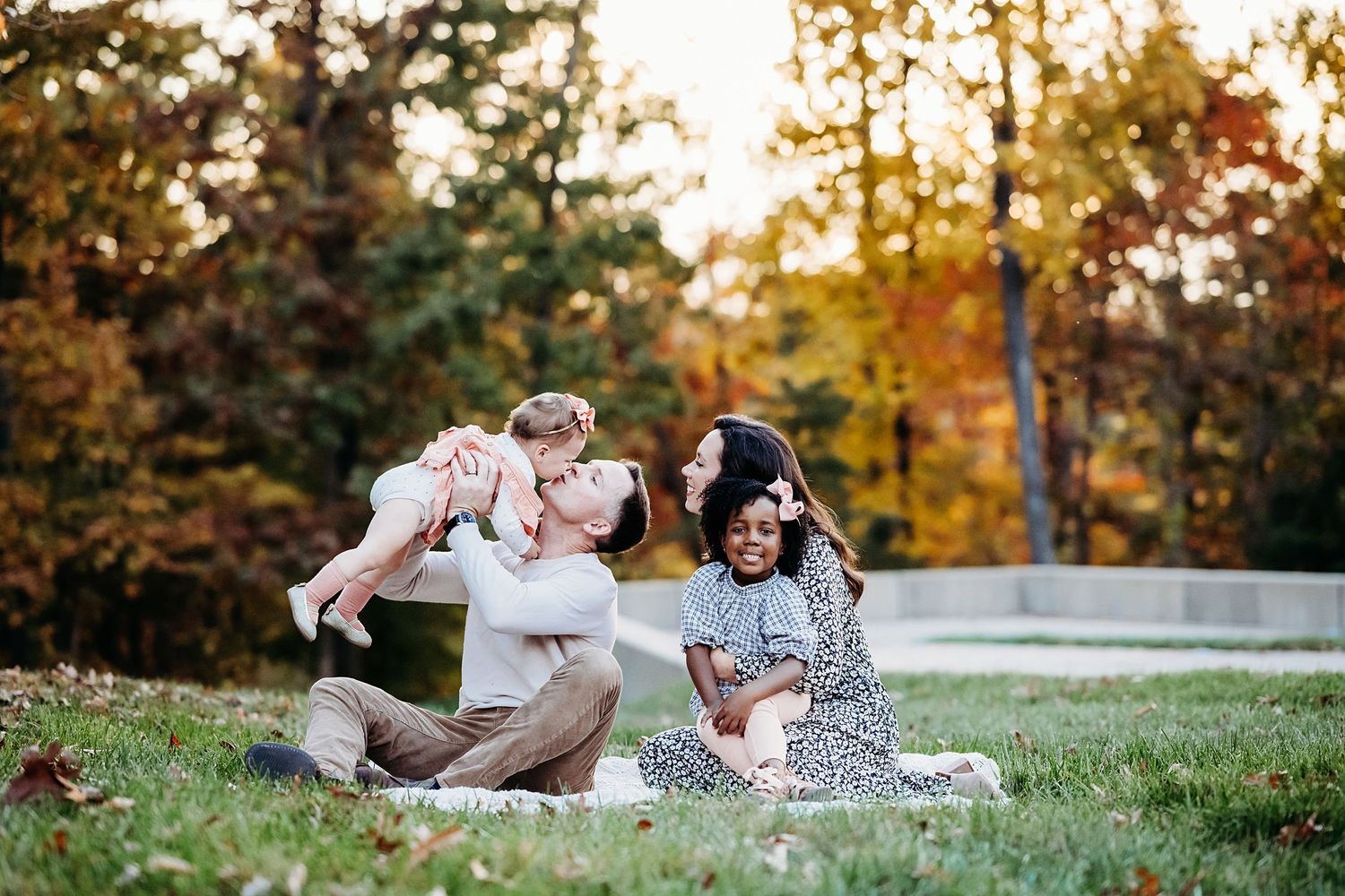 Family photography session on grassy hill during golden hour in autumn.