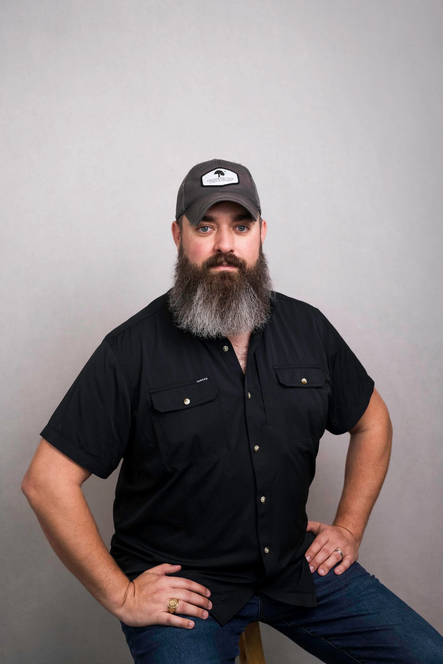 Studio portraits showing casual poses in black shirt and baseball cap against grey background.