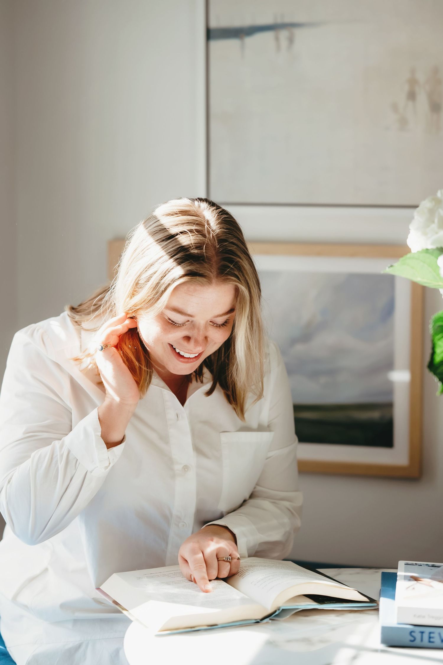 Creative workspace photos showing someone reading and working at a desk with fresh flowers nearby.
