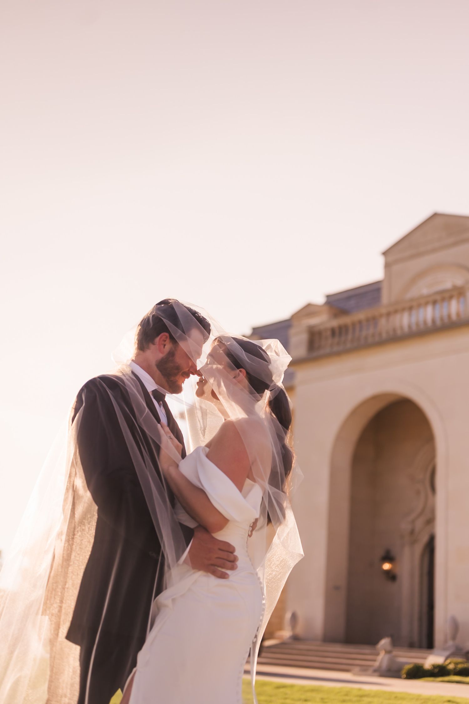 Romantic sunset wedding portraits against cream colored Mediterranean architecture.