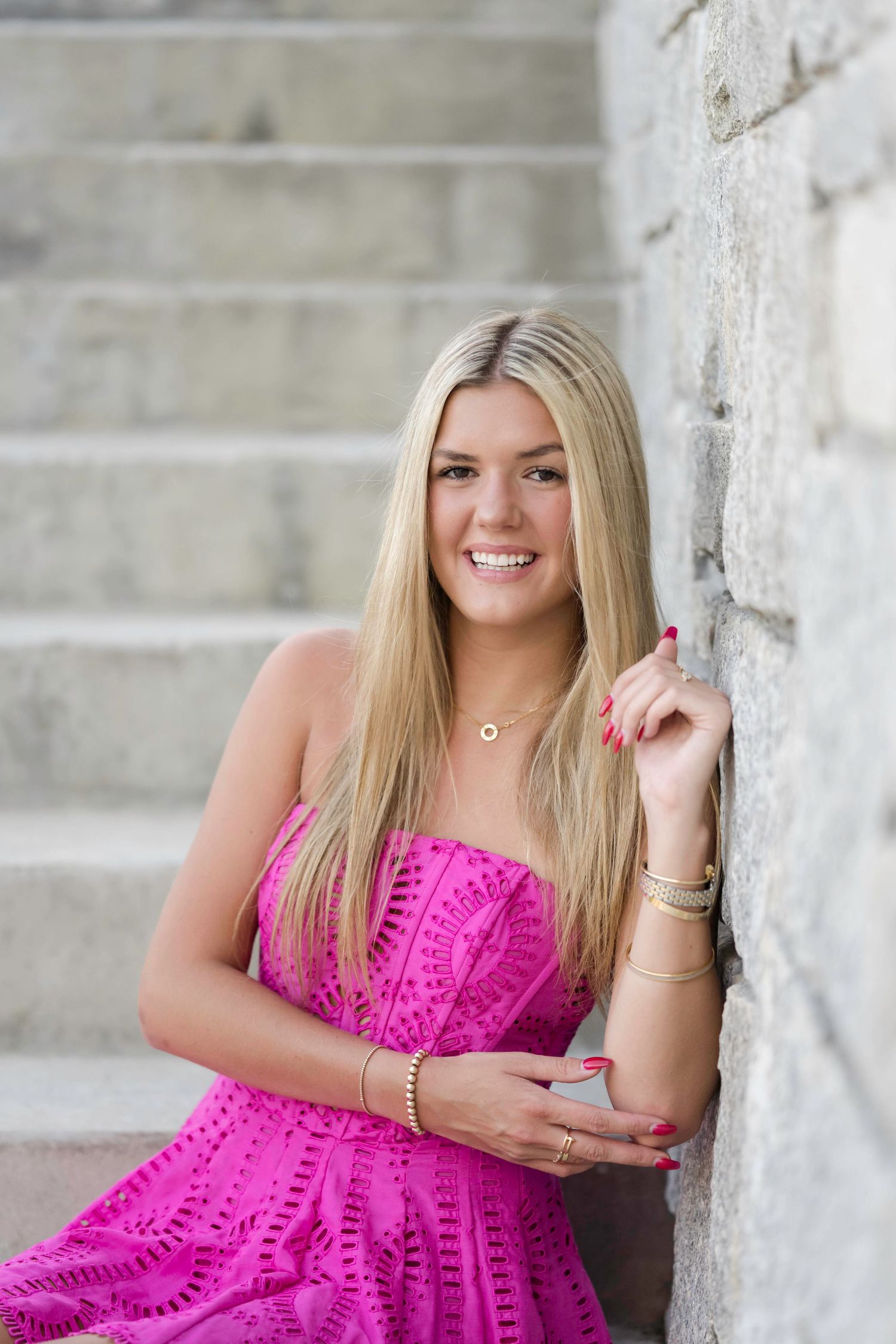 Portrait against stone stairway wearing bright pink dress.