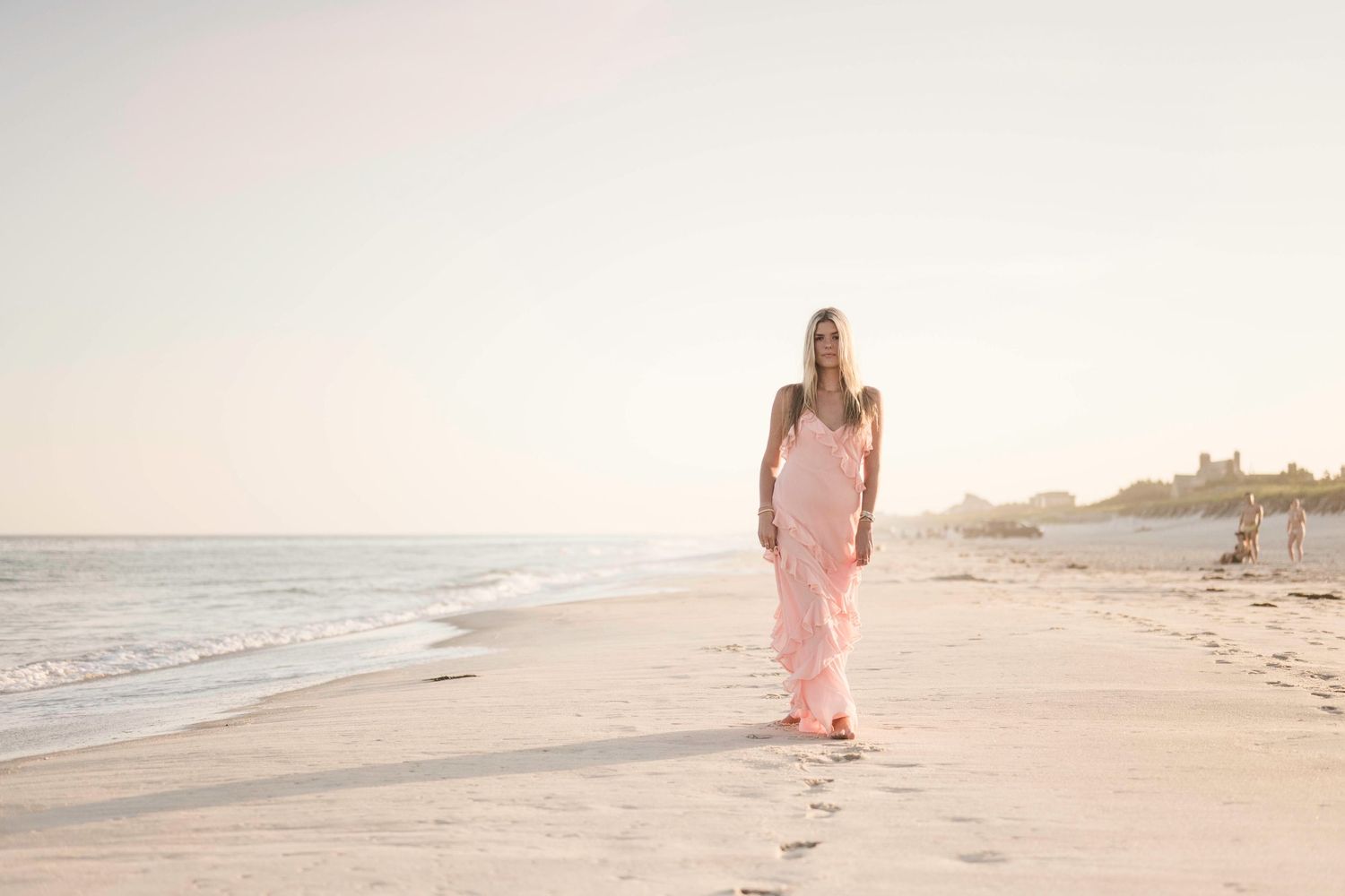 A peaceful beach scene at sunset with pink dress silhouetted against the shoreline.