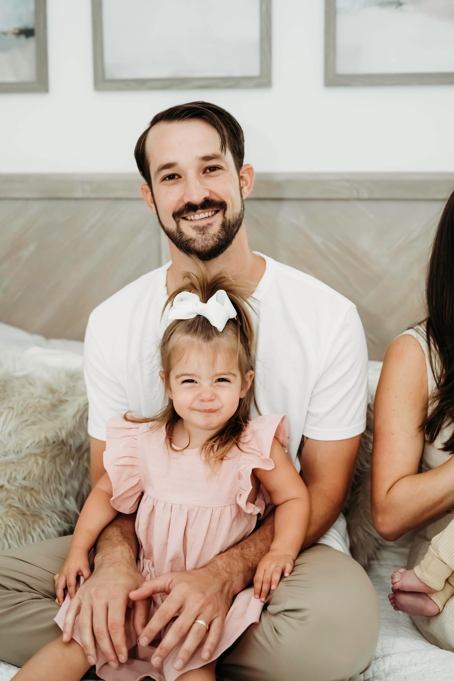 A cozy family portrait session on a light gray couch with soft neutral clothing.