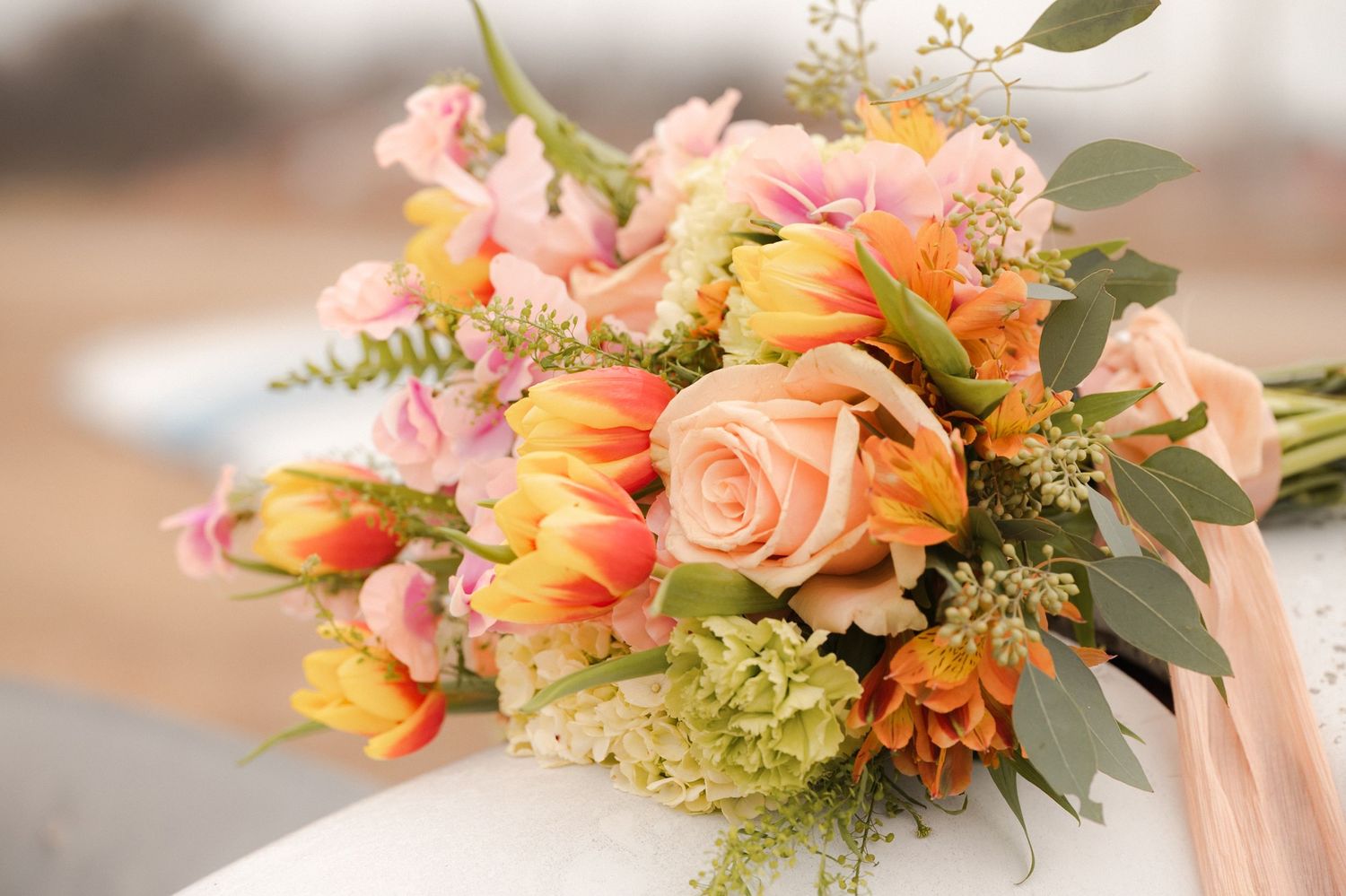Elegant coral and peach floral centerpieces with roses and greenery arranged for a wedding reception table.