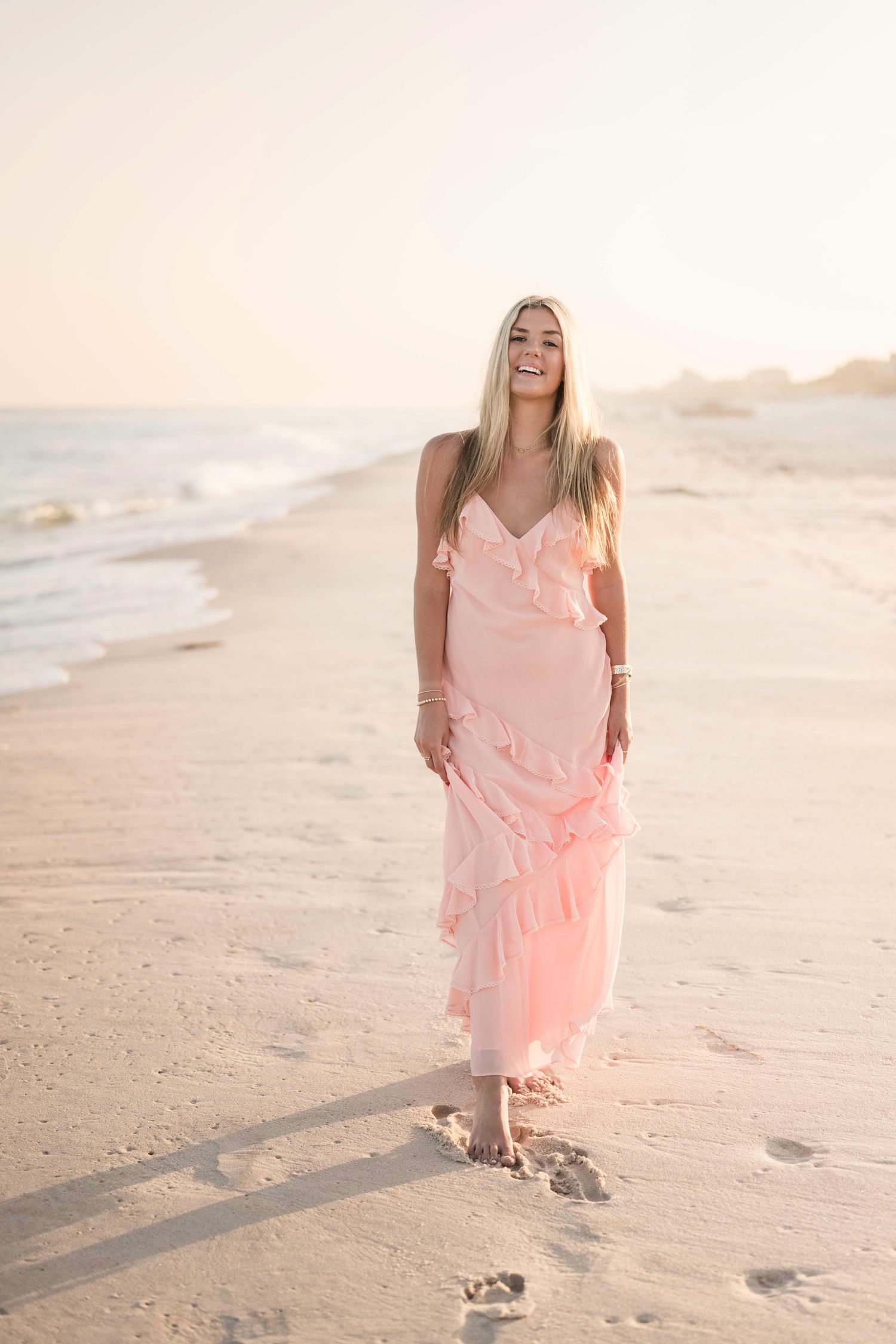 Footprints trail behind in the sand during a beachside photo session at golden hour.