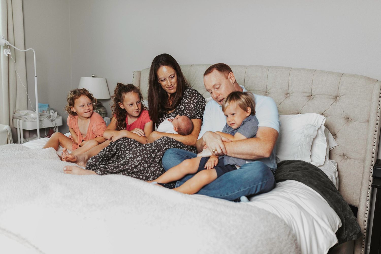 Family members lying together on a bed sharing intimate bonding moments in black and white photography.