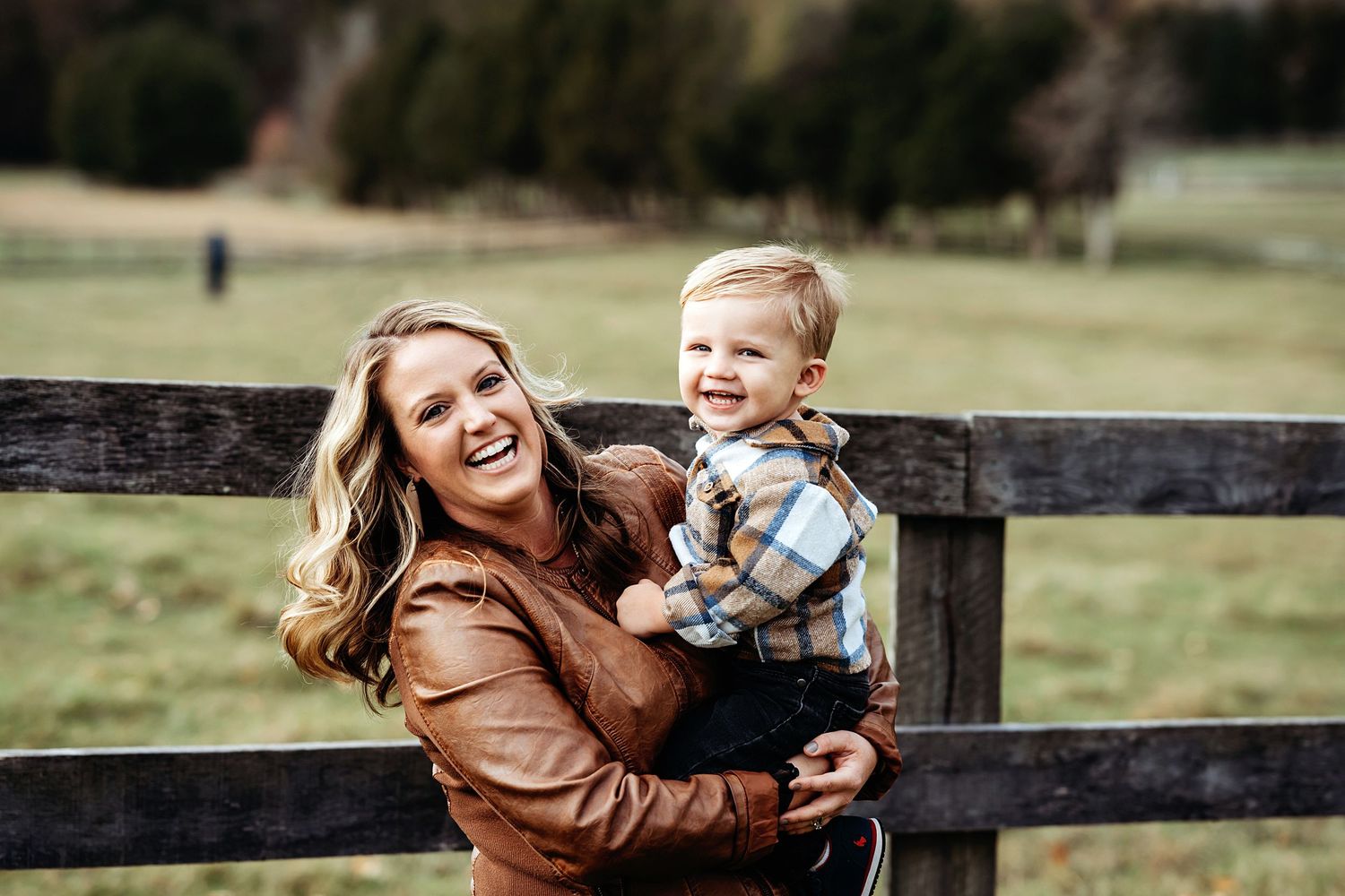 Candid family moment captured against wooden fence during fall photo session.
