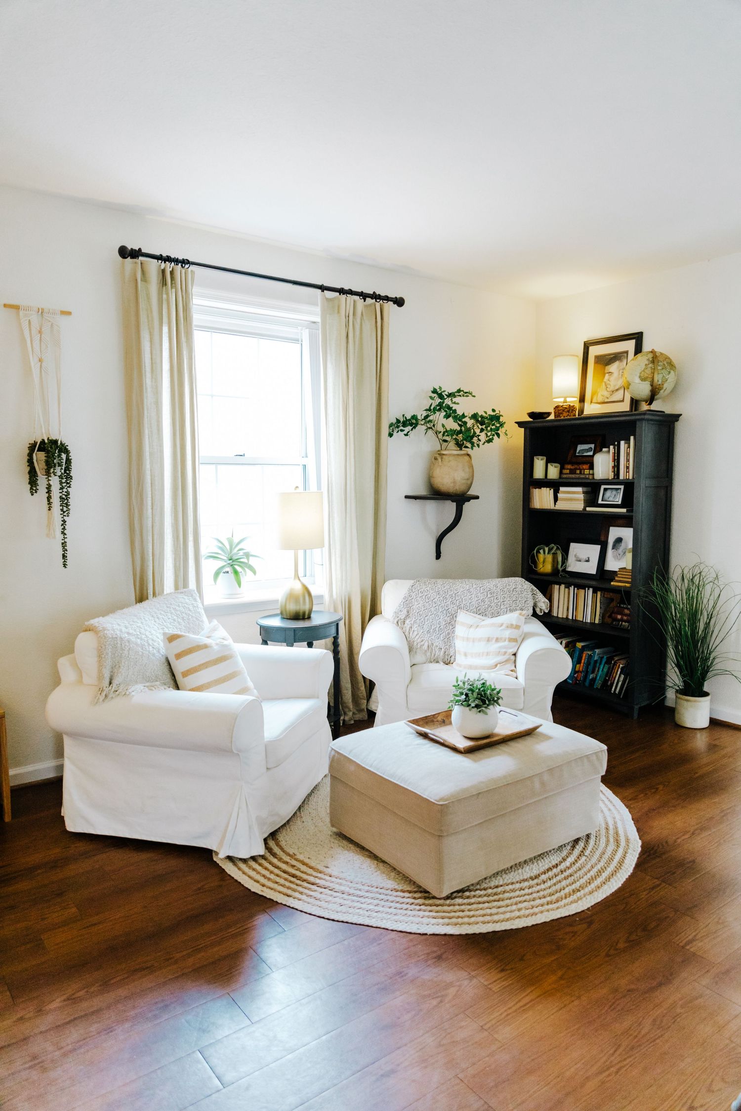 Bright living room with white slip-covered furniture, round jute rug, and hardwood floors.