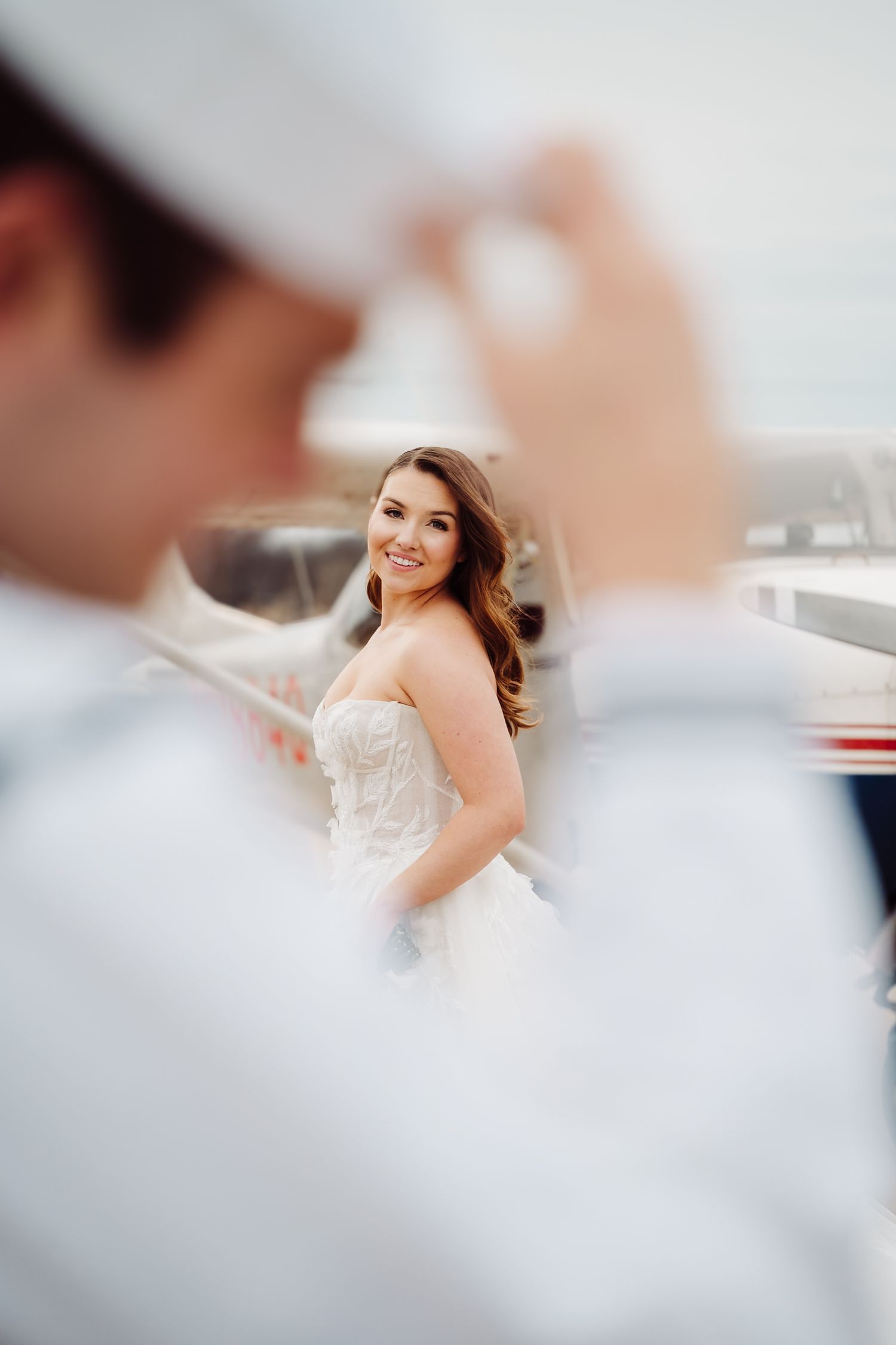 A bride in a white wedding dress poses with a joyful expression during a wedding photo session.