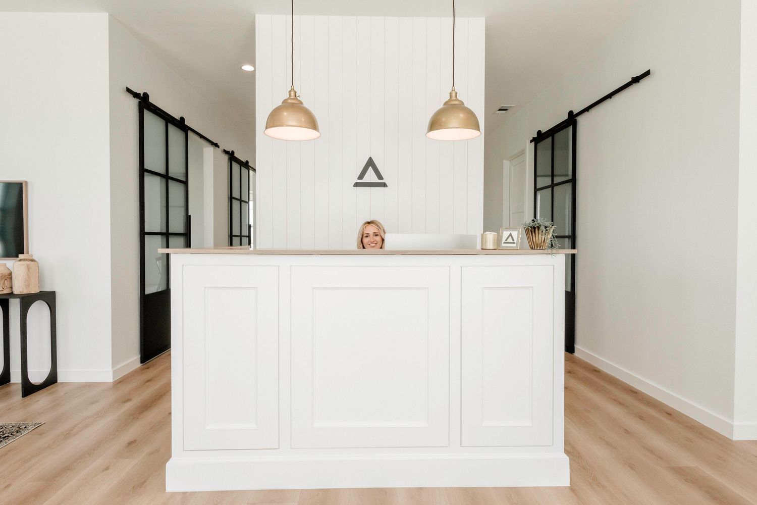 A modern white kitchen features pendant lights, hardwood floors, and a sleek minimalist design with clean lines.