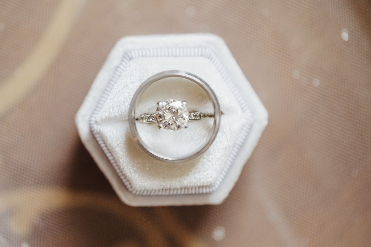Diamond engagement ring and wedding band displayed in a white hexagon velvet ring box.