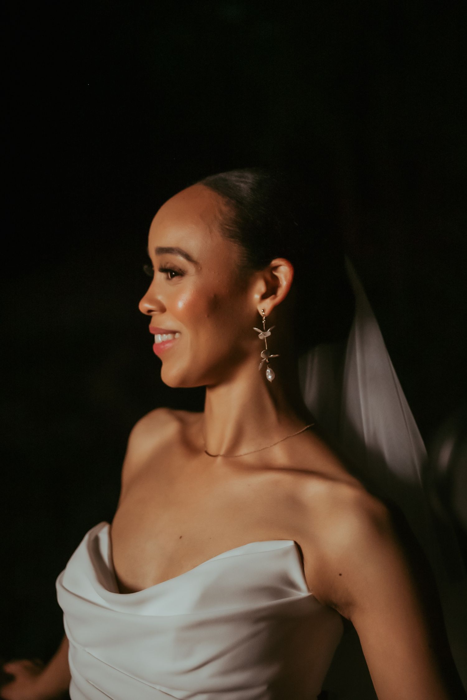 Close-up portrait shots of a bride in a white strapless wedding dress with dramatic lighting against dark background.