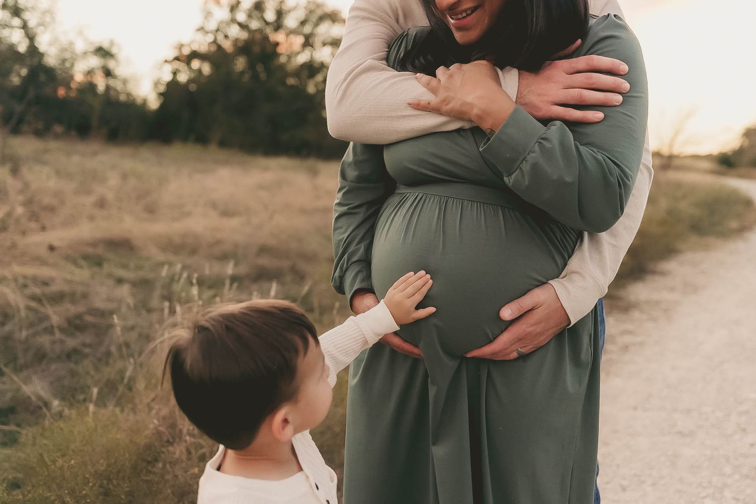 A couple embraces tenderly during a golden hour photoshoot on a rustic dirt path.
