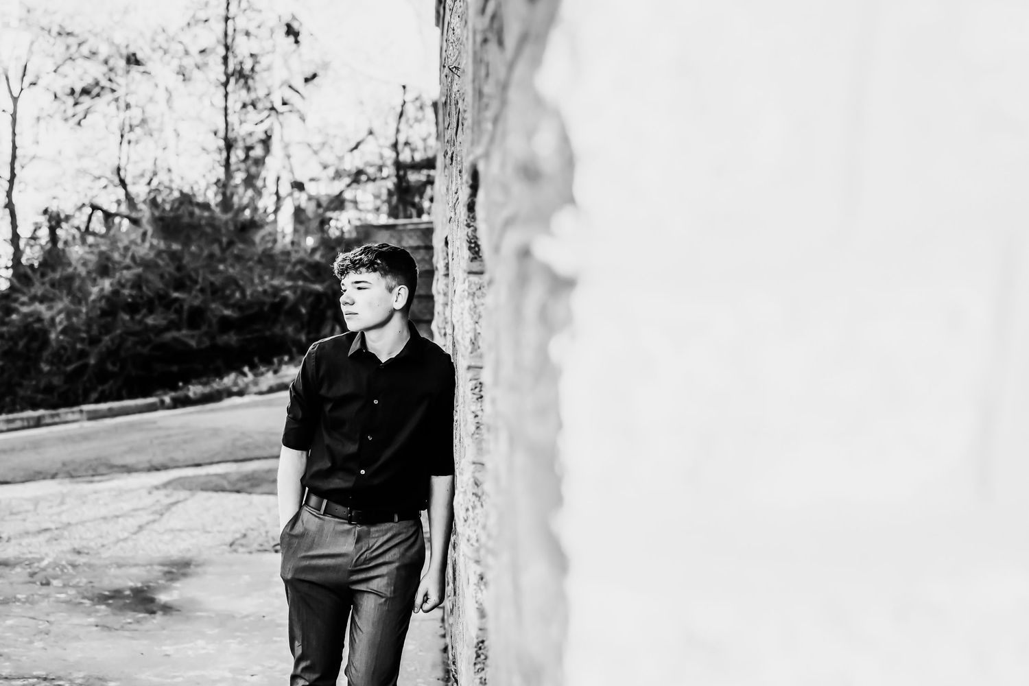 Atmospheric black and white portrait taken against a light outdoor background.