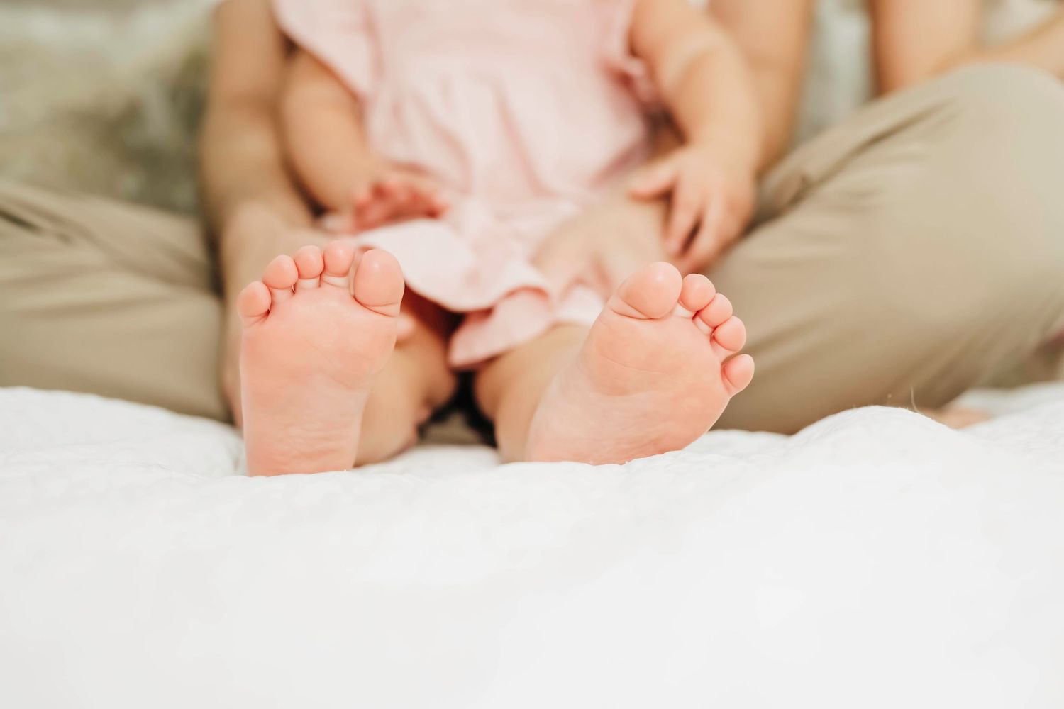 Tiny newborn baby feet gently resting on soft beige blankets.