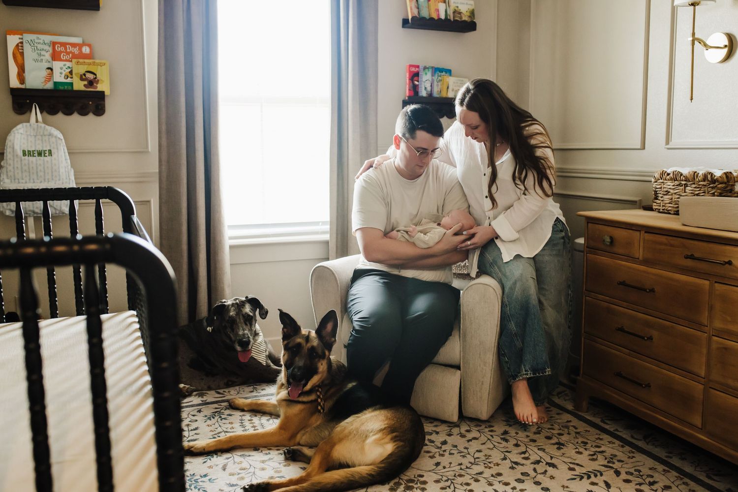 A couple sits together on a couch in their living room while their dog rests nearby.