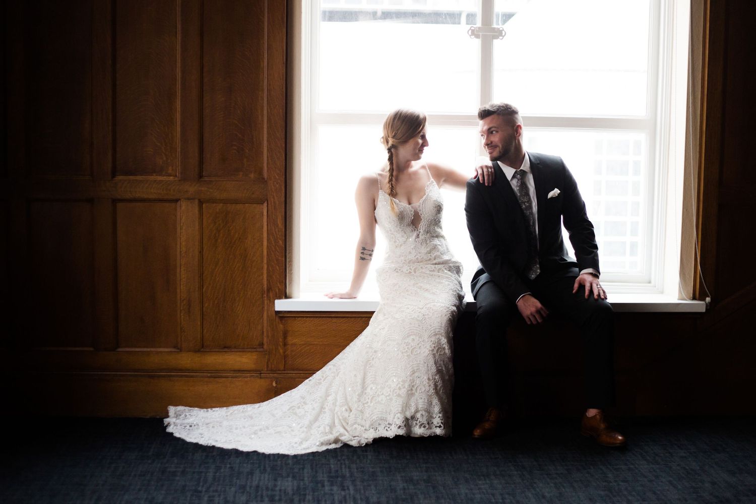 A bride and groom share an intimate moment in front of a window in a rustic wooden room.by Knot & Wing Photography