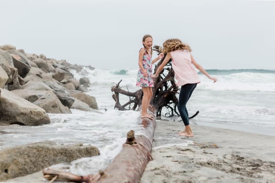 Family enjoying time together on a rocky beach by the ocean.