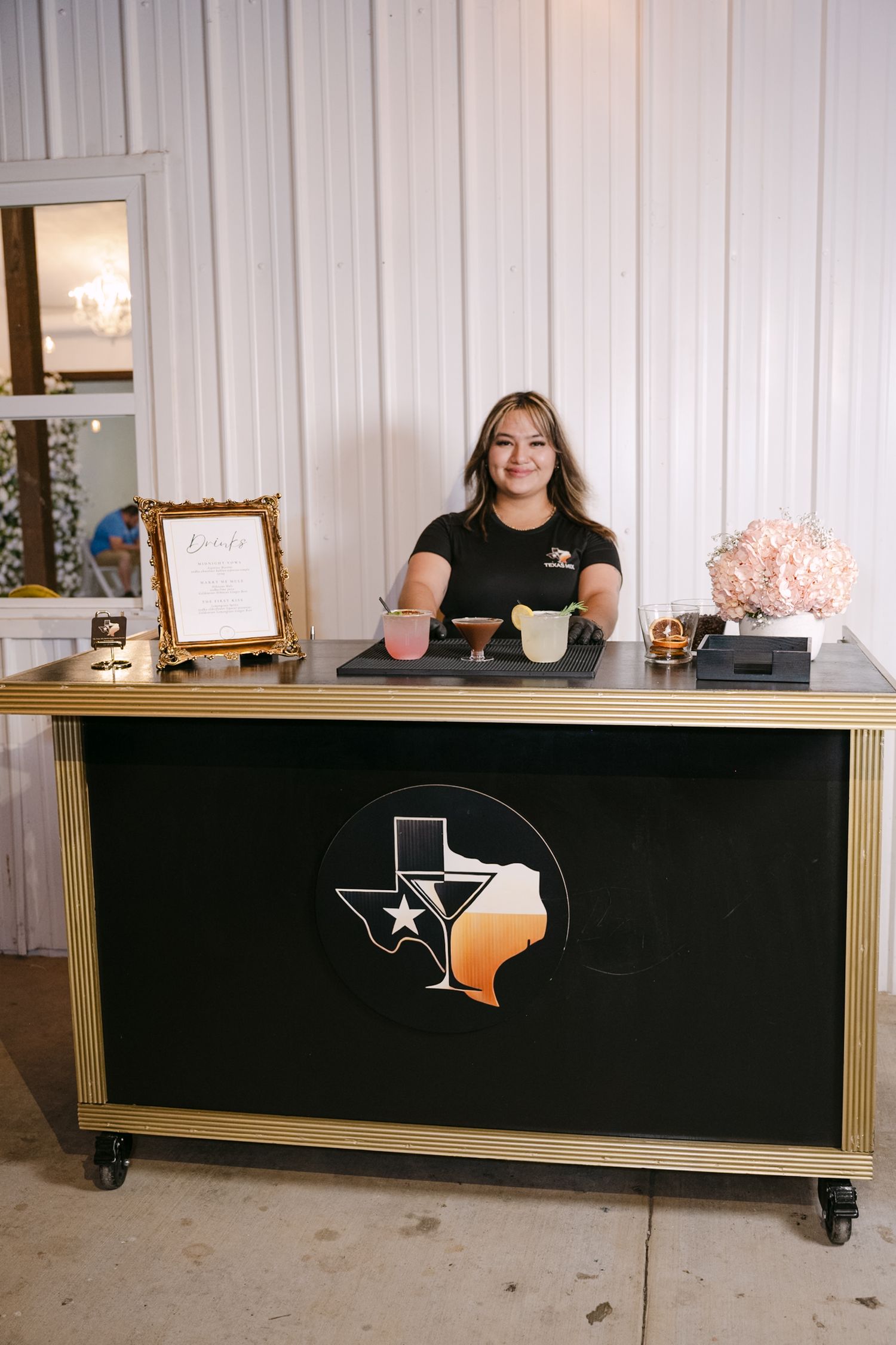 Custom black and gold mobile bar with Texas state design on rolling wheels in a studio setting.