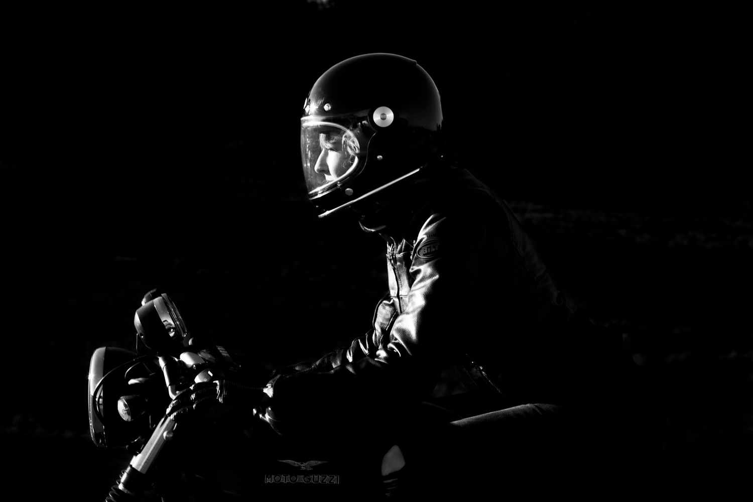 A dramatic black and white image of a motorcyclist riding.