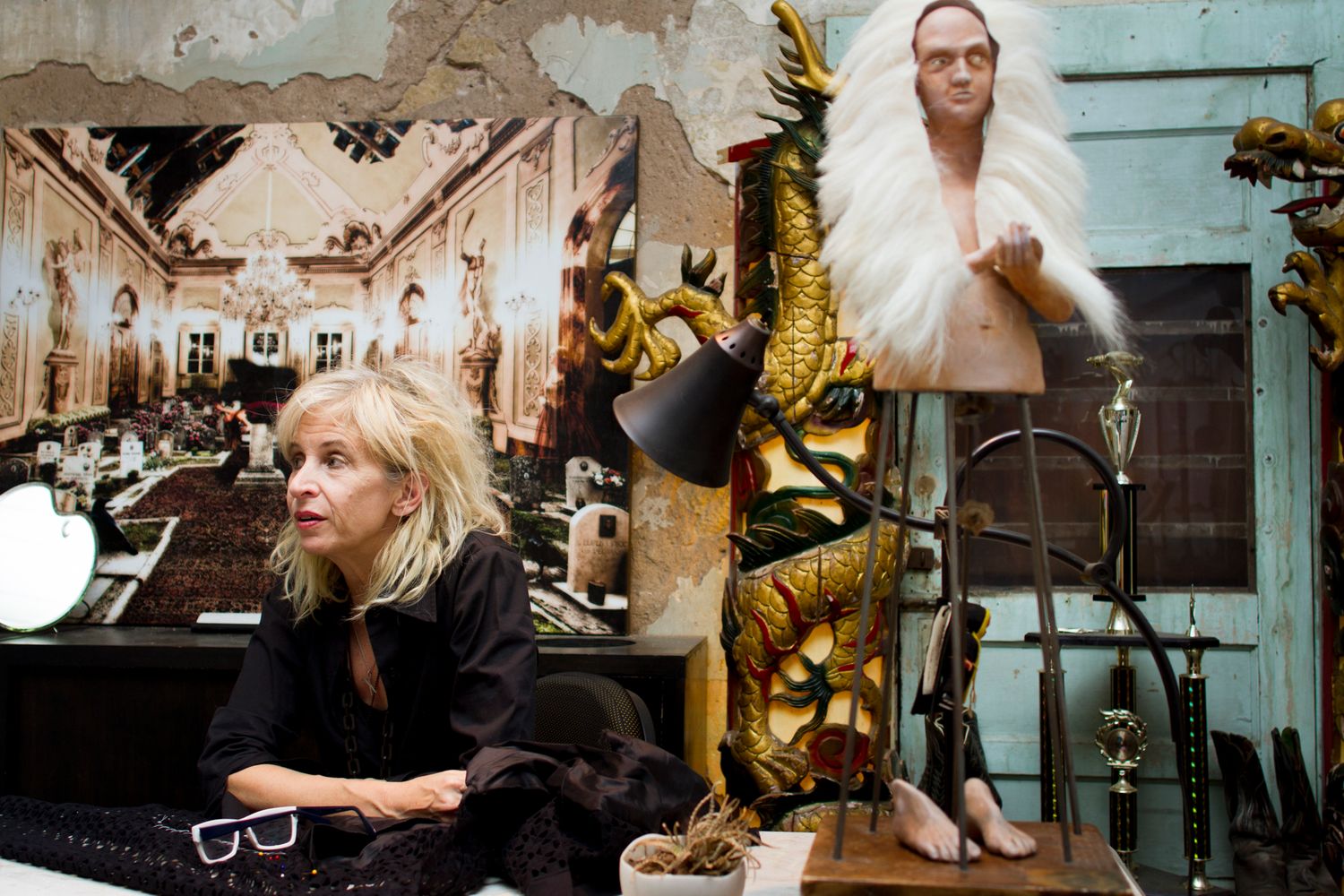 Designer, Gail Chovan, holding a discussion while seated at her desk with vintage decor and wooden elements in the background.