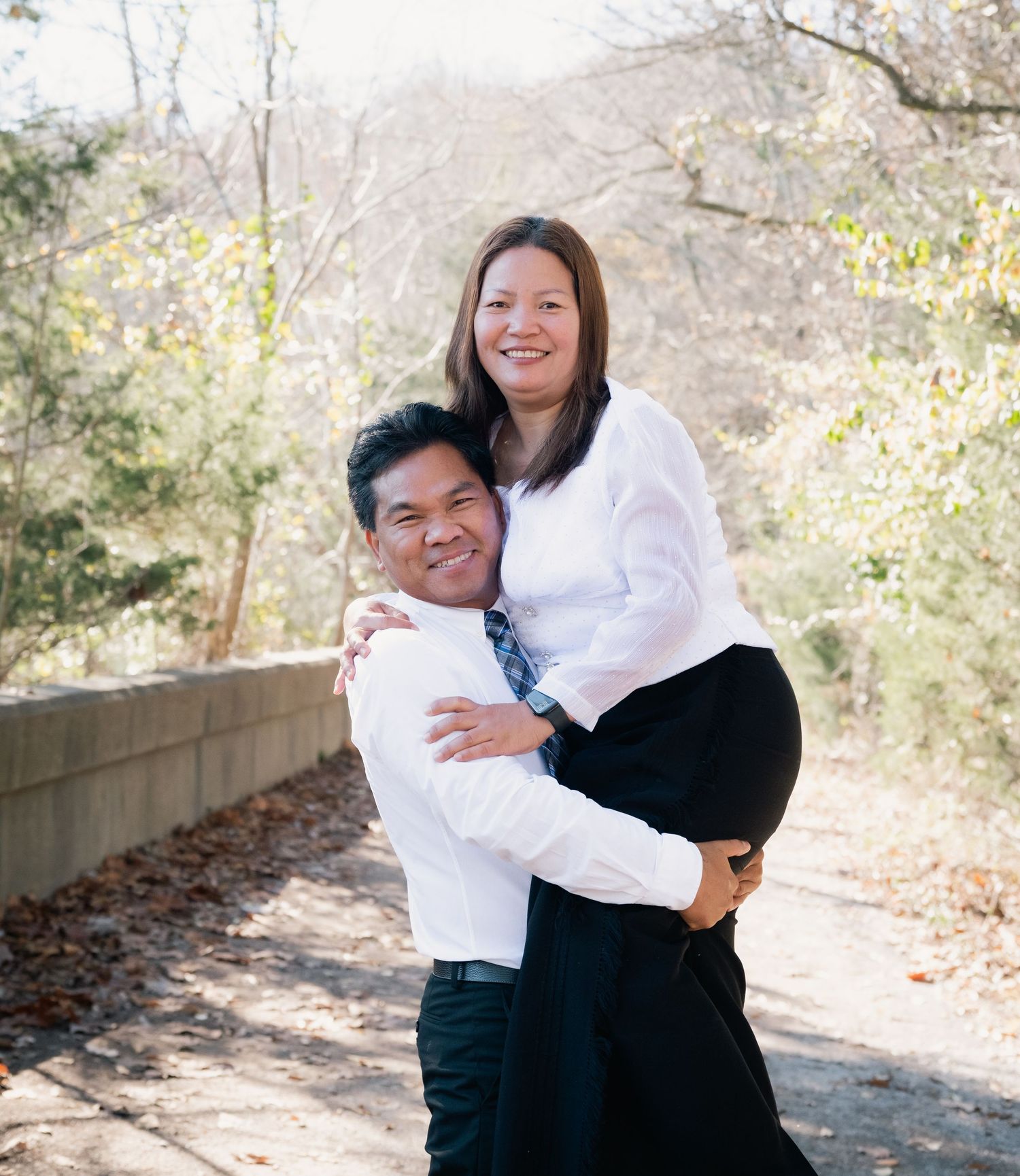 A couple embraces and laughs together during their outdoor photo session in matching attire.