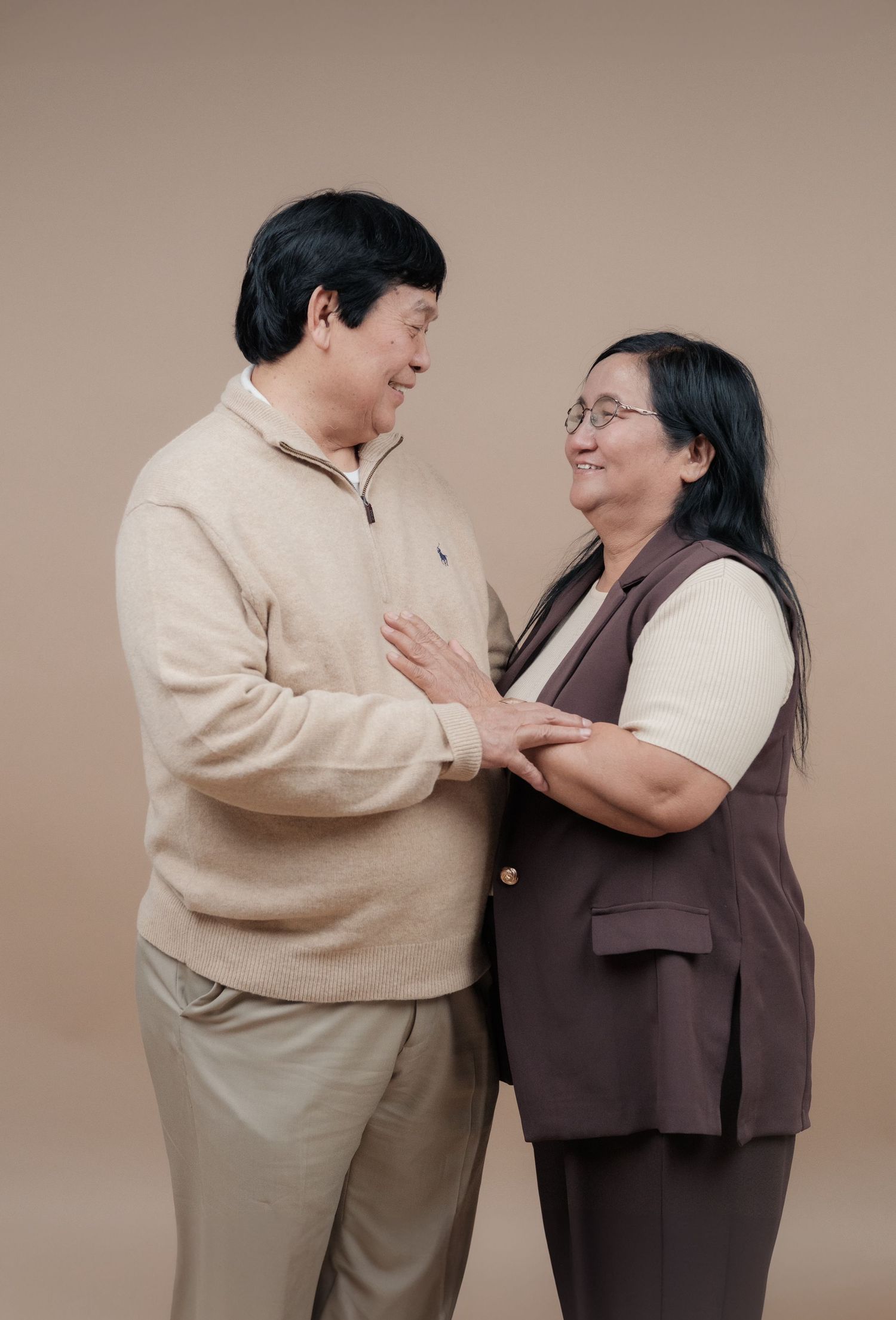 A couple sharing an intimate moment while wearing coordinated beige and brown outfits.