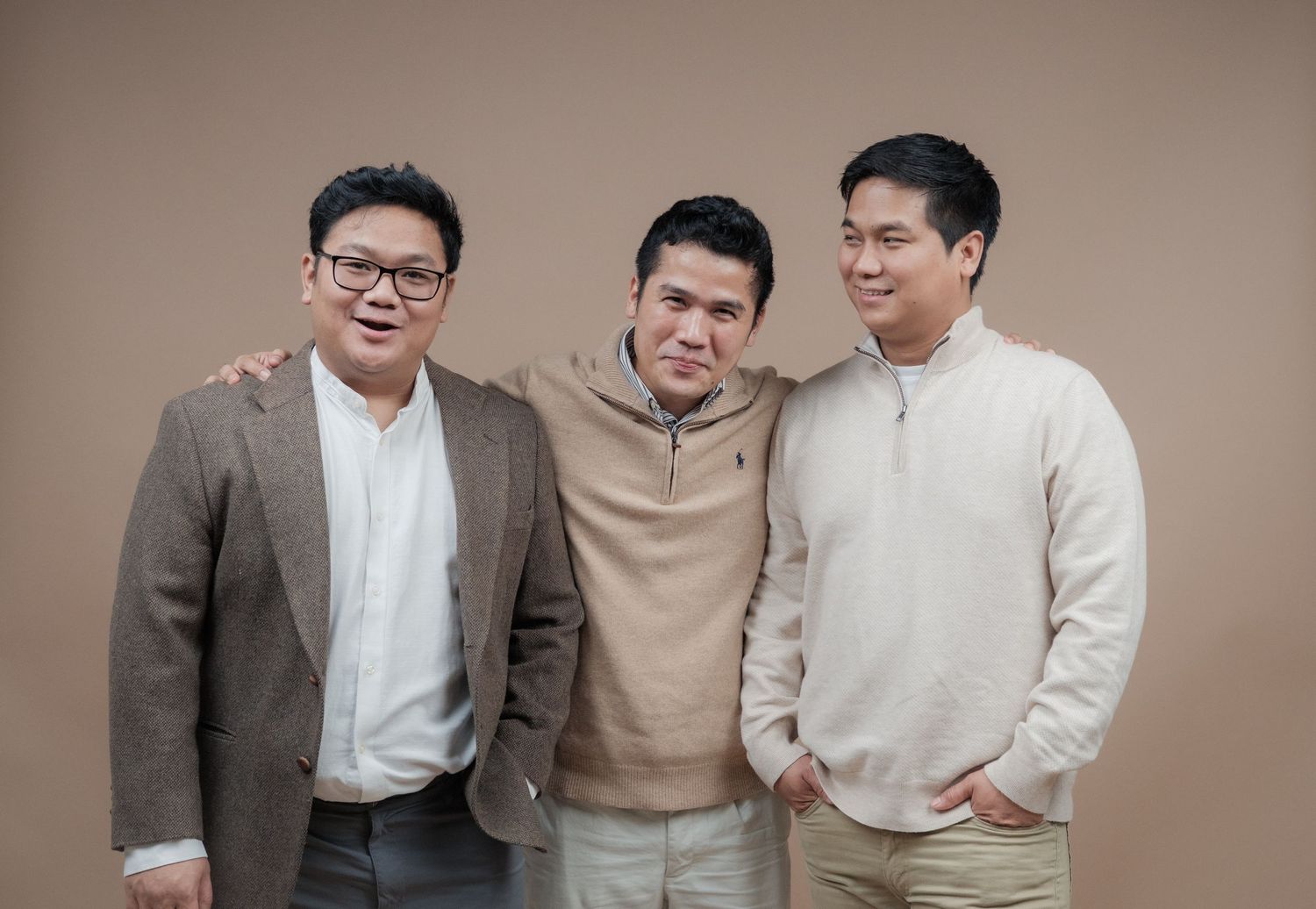 Three people in business casual attire share a laugh during a professional photo session.
