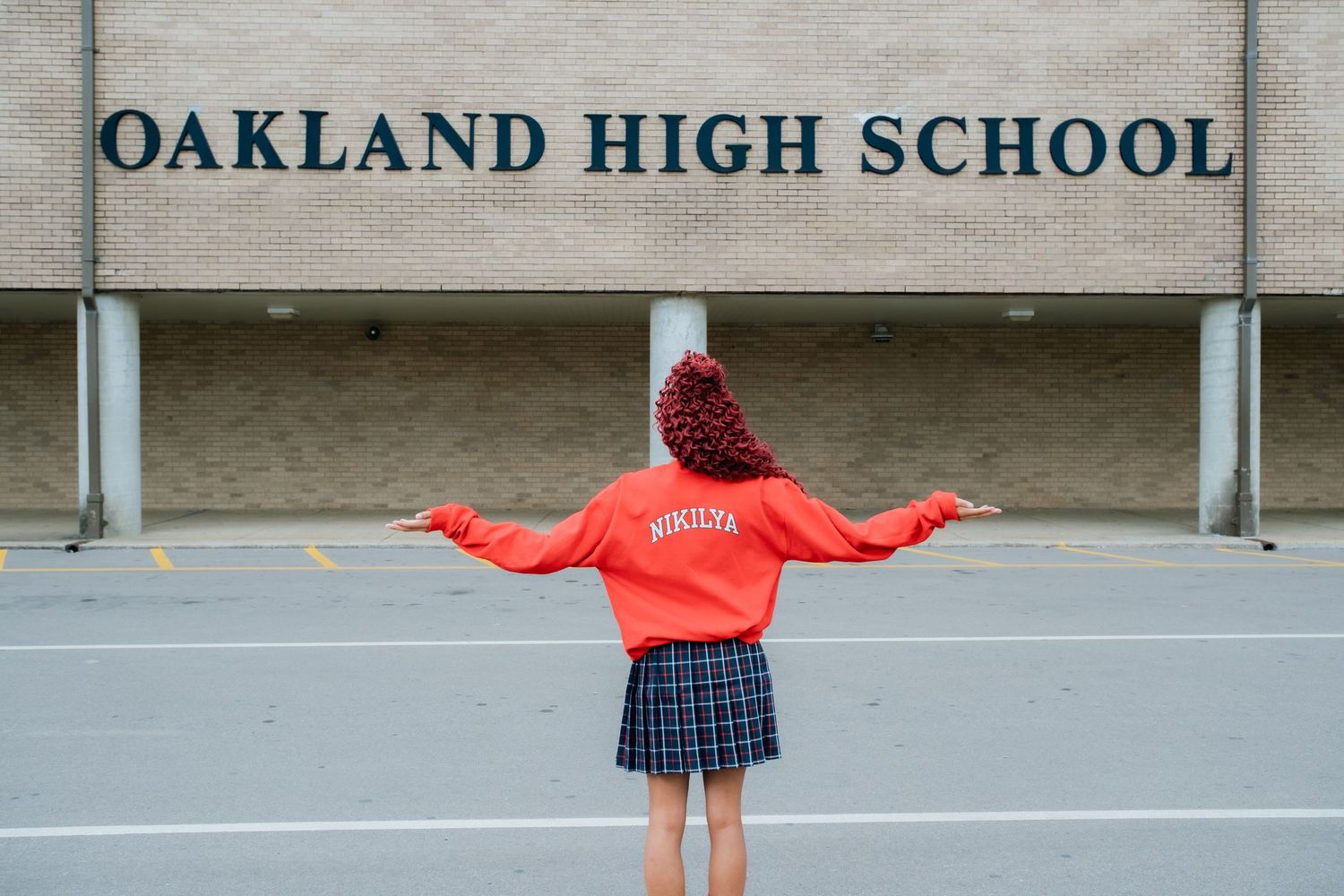 Student poses in front of Oakland High School entrance sign.