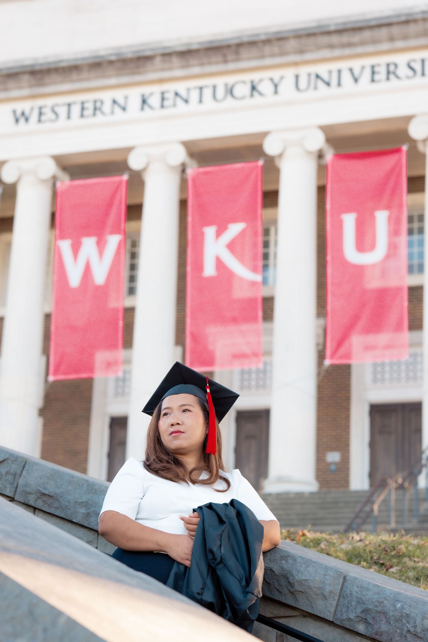 Graduate posing in front of Western Kentucky University's iconic colonnade.