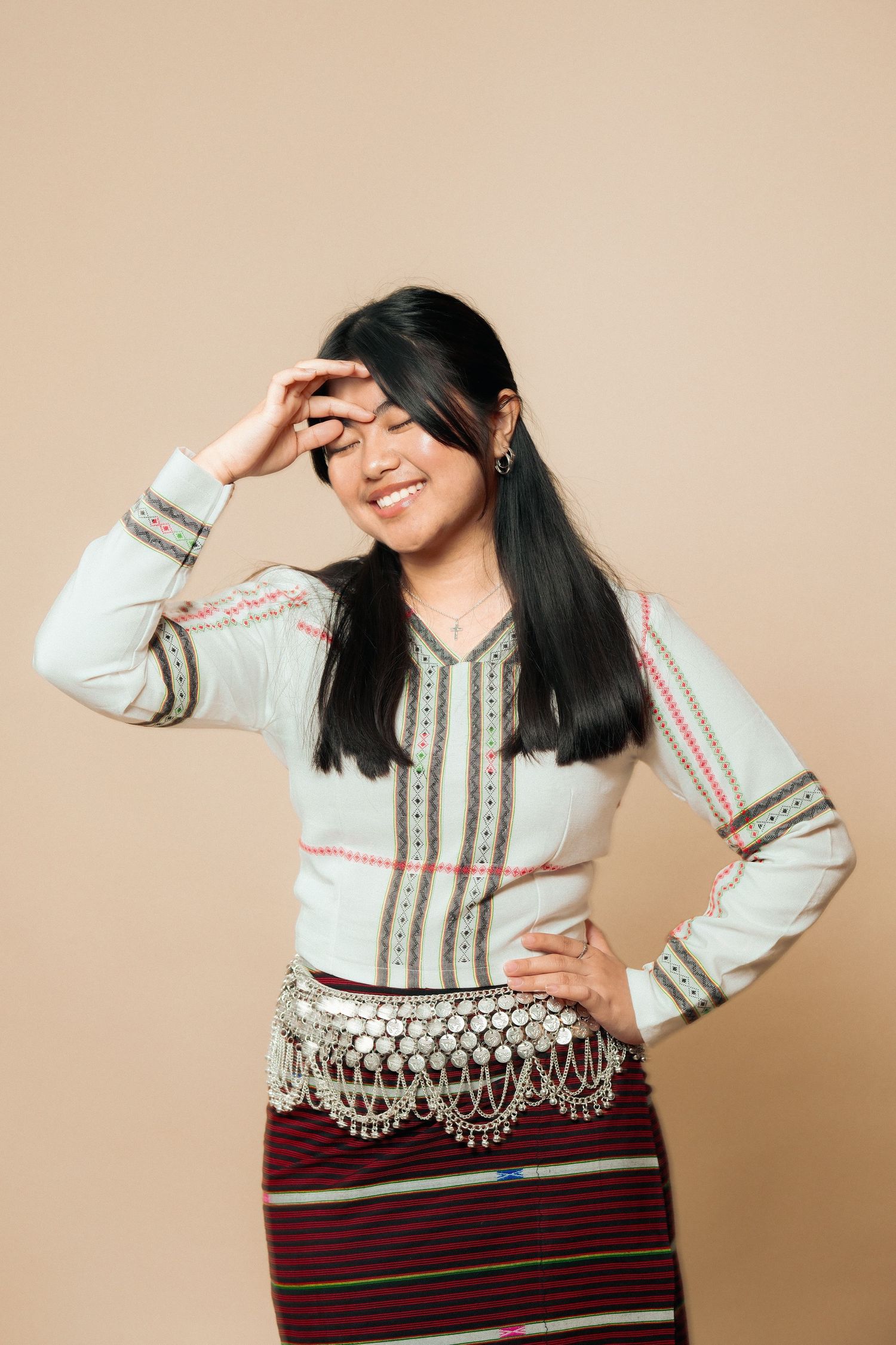 Person in ethnic attire performs expressive dance moves in studio setting.