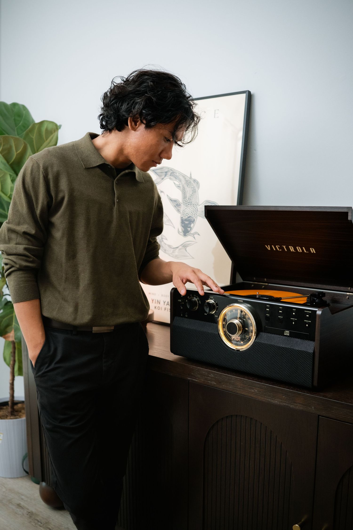 Person examining a vintage record player in an aesthetically styled room.